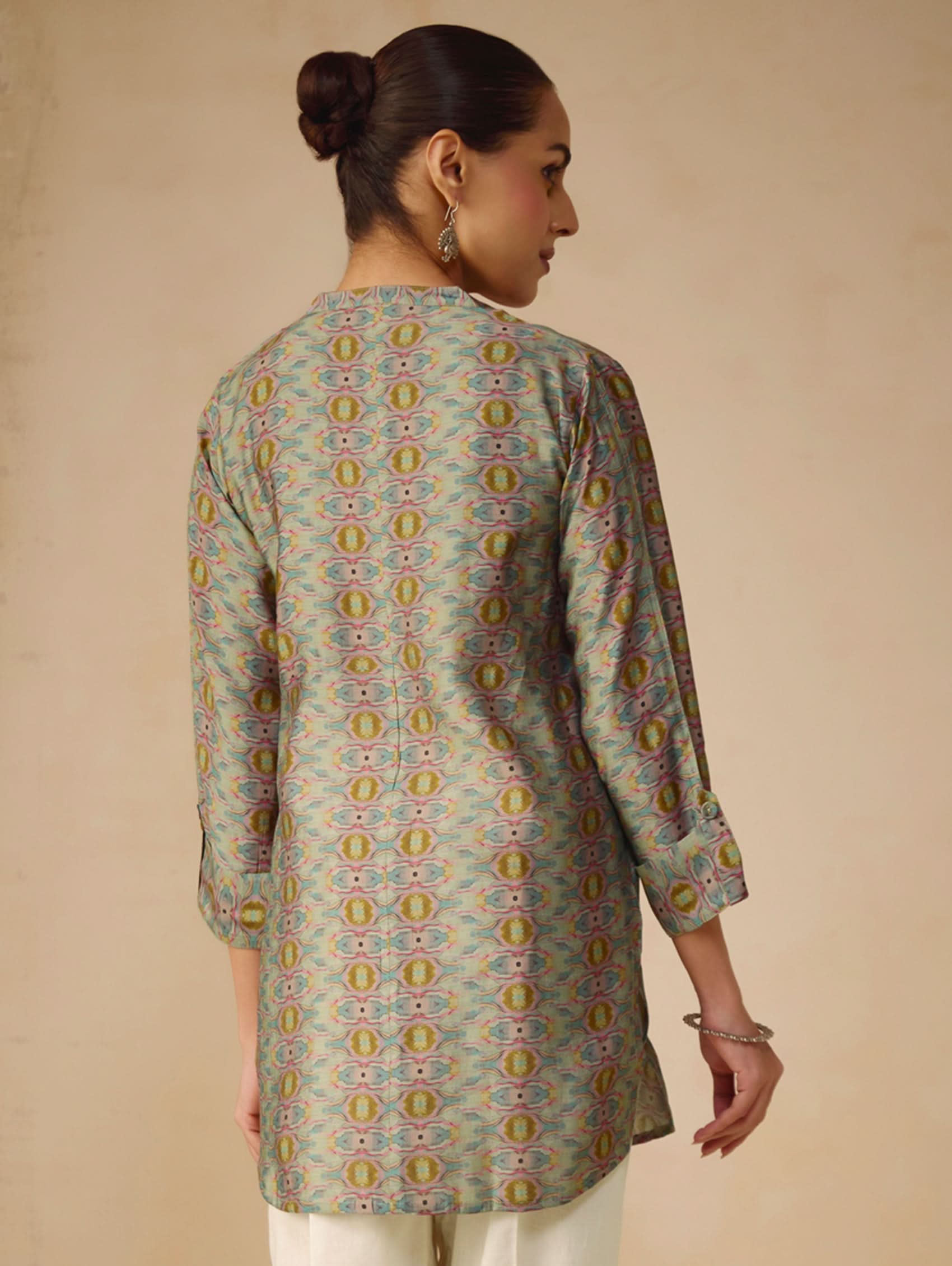 Woman wearing a patterned kurta against a beige background