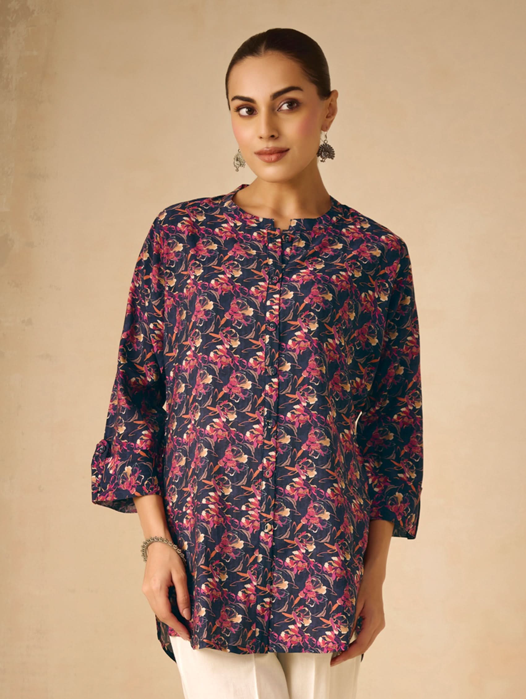 Woman wearing a floral patterned kurta against a beige background