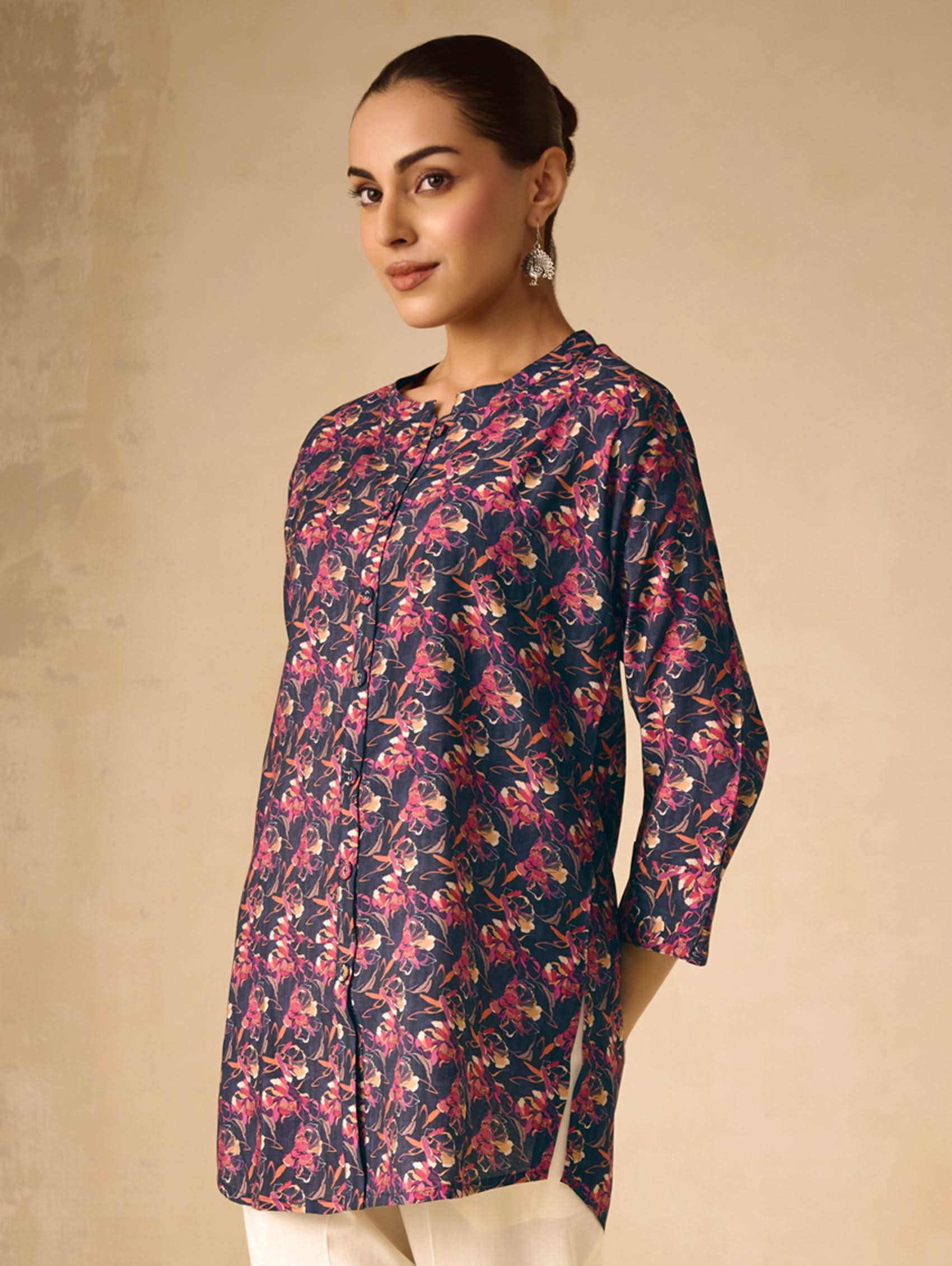 Woman wearing a floral patterned kurta against a beige background