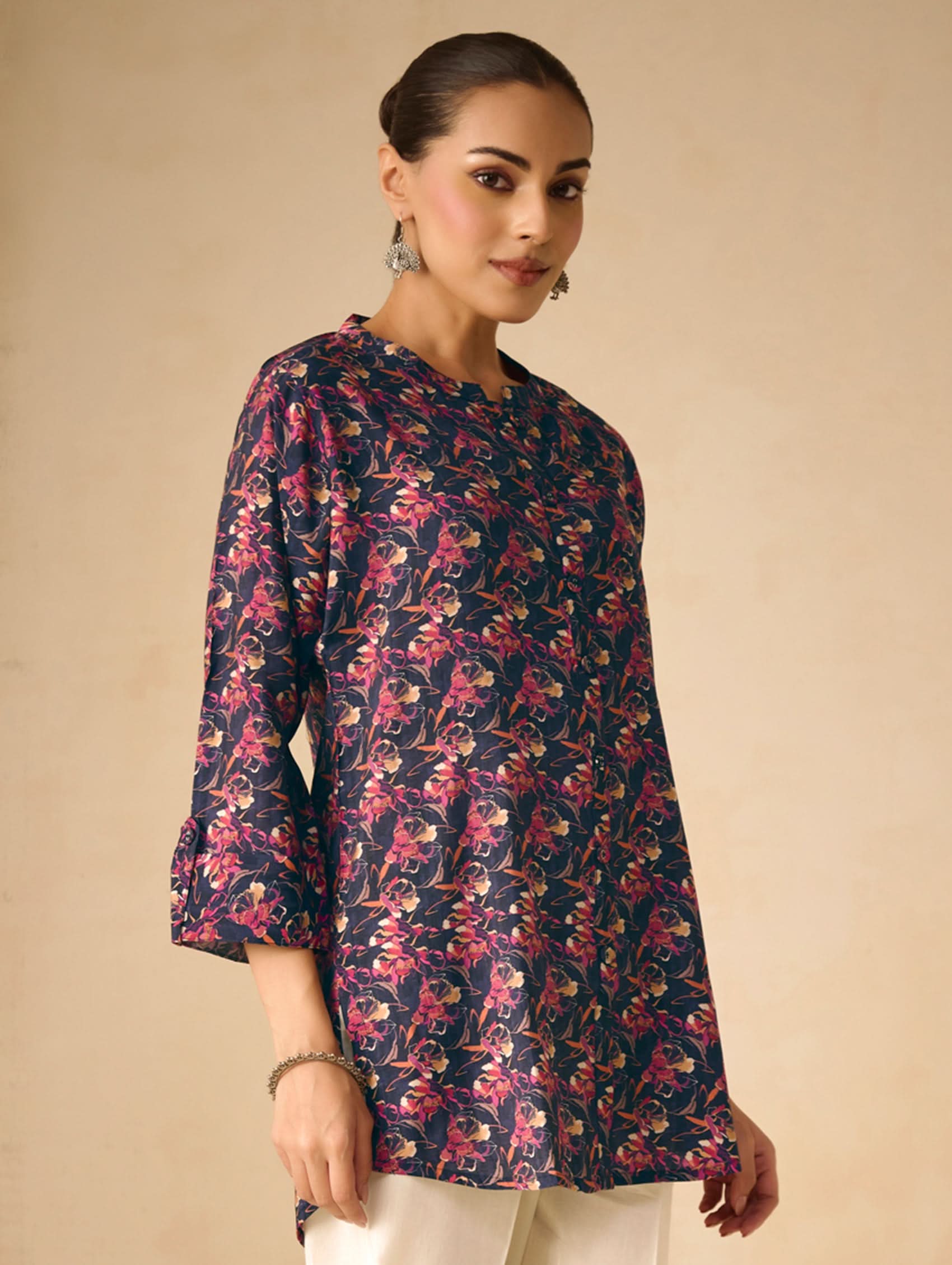 Woman wearing a floral patterned kurta against a beige background