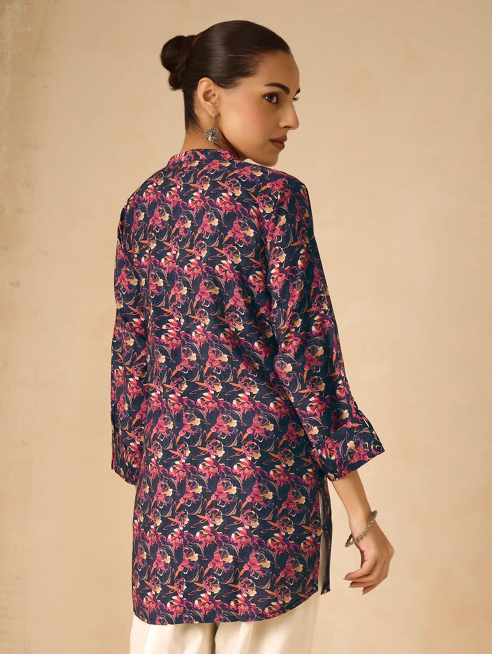 Woman wearing a floral patterned shirt against a beige background