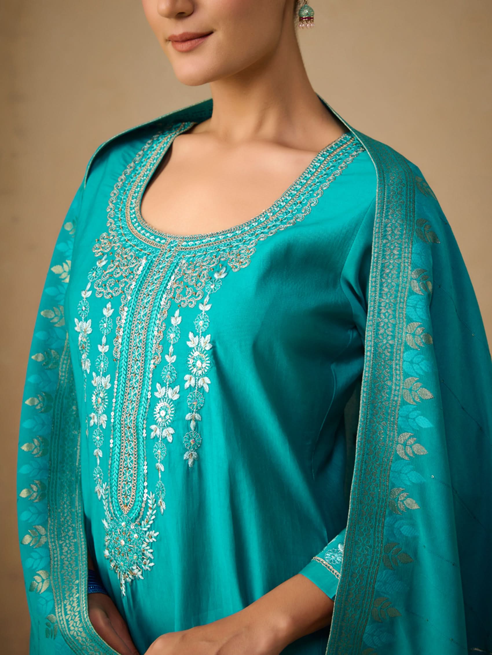 Teal embroidered garment with a neutral background