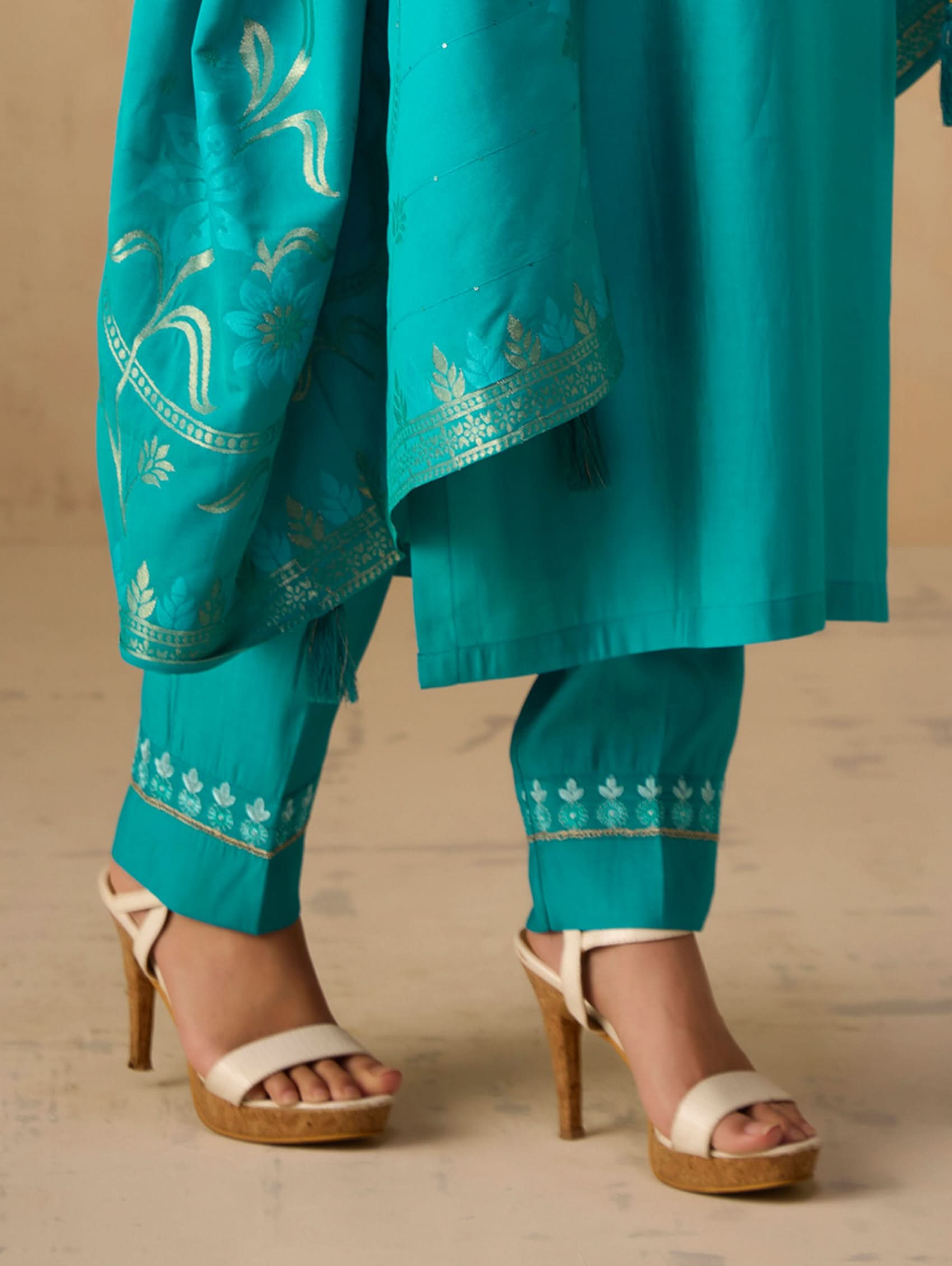Teal embroidered outfit with matching pants and sandals on a neutral background