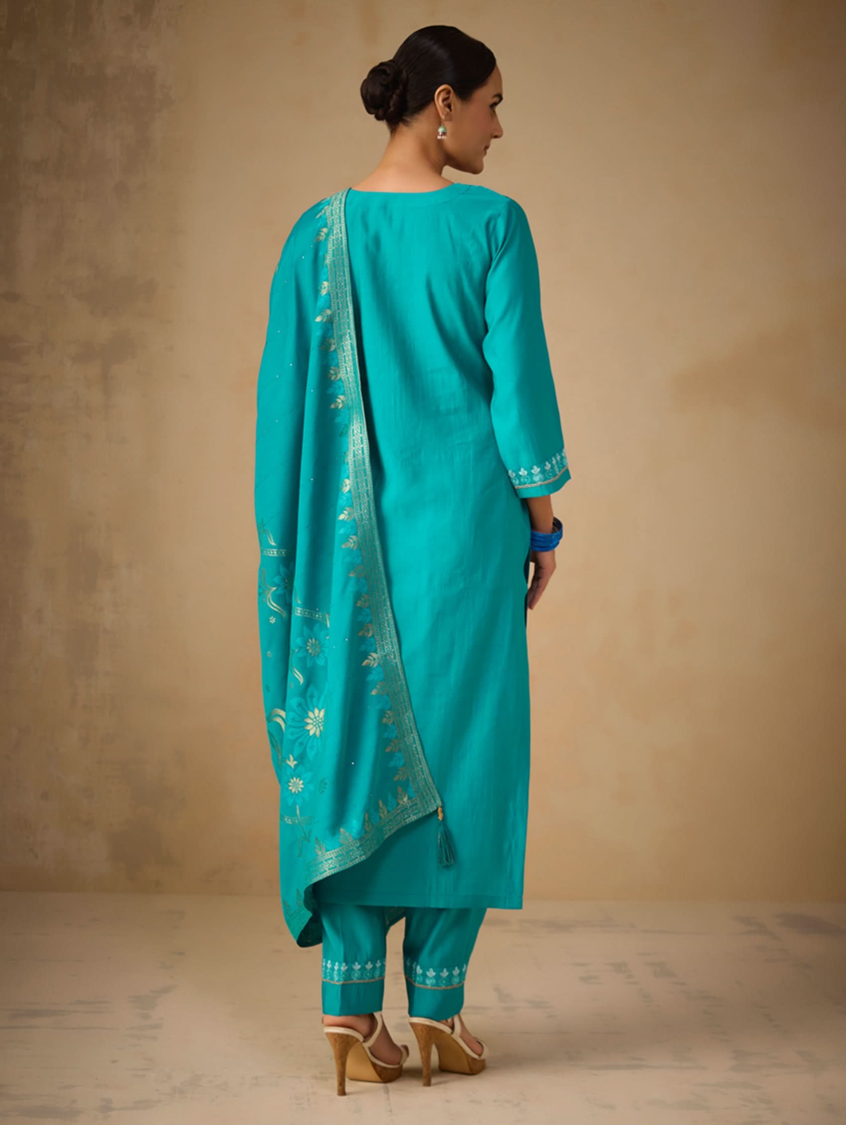 Woman wearing a turquoise traditional outfit with a plain background