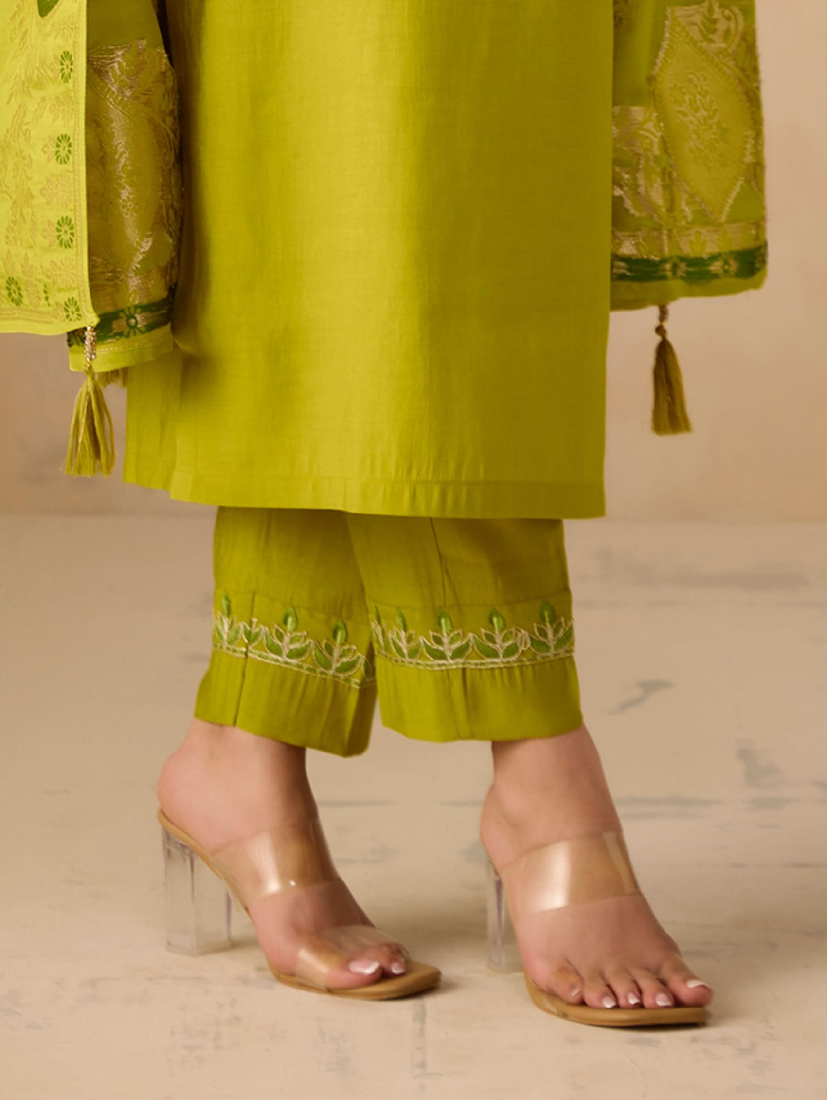 Lime-green pants with embroidered hem and gold trim, worn with heels