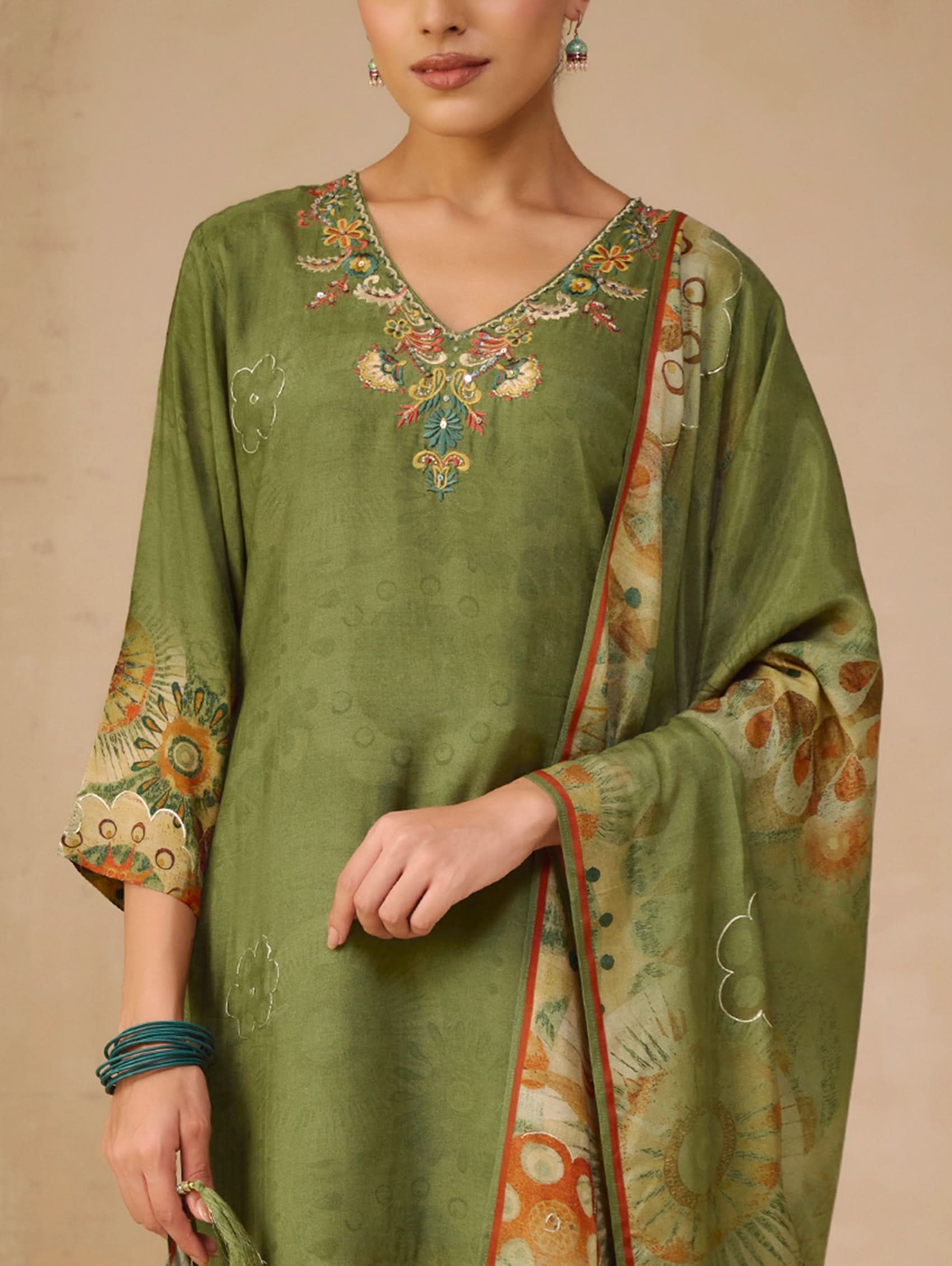 Green embroidered traditional outfit with a matching dupatta on a beige background