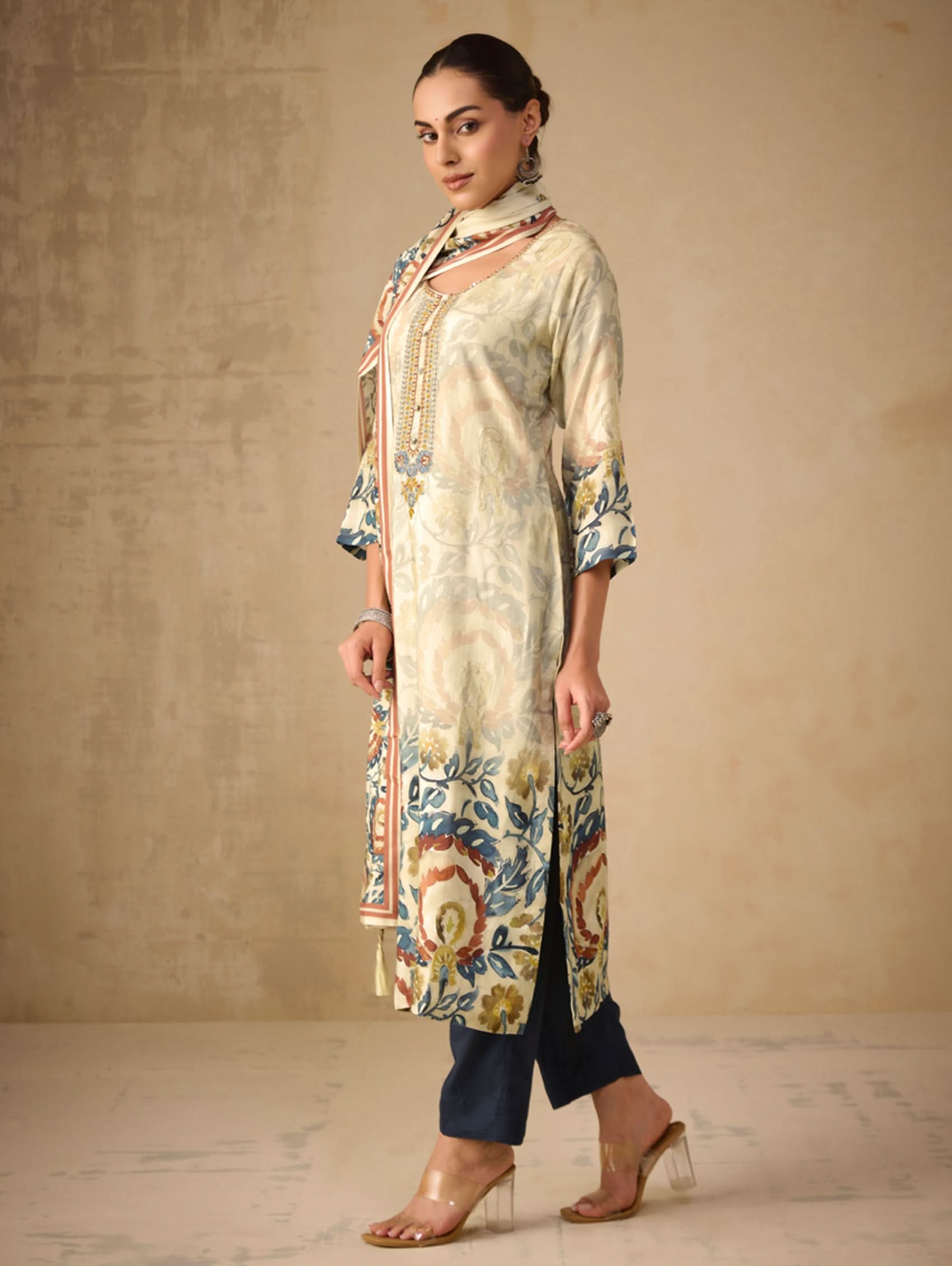Woman wearing a floral kurta with navy pants against a beige background