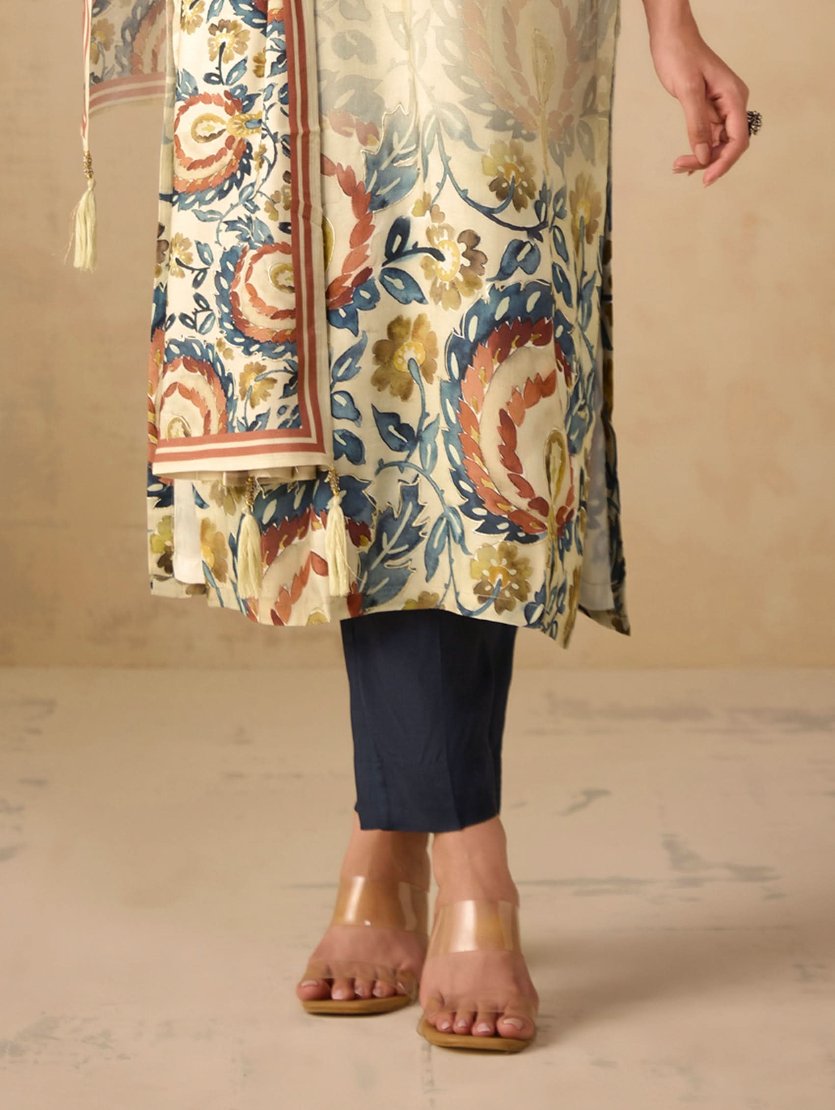 Traditional outfit with floral patterned top and navy pants on a neutral background