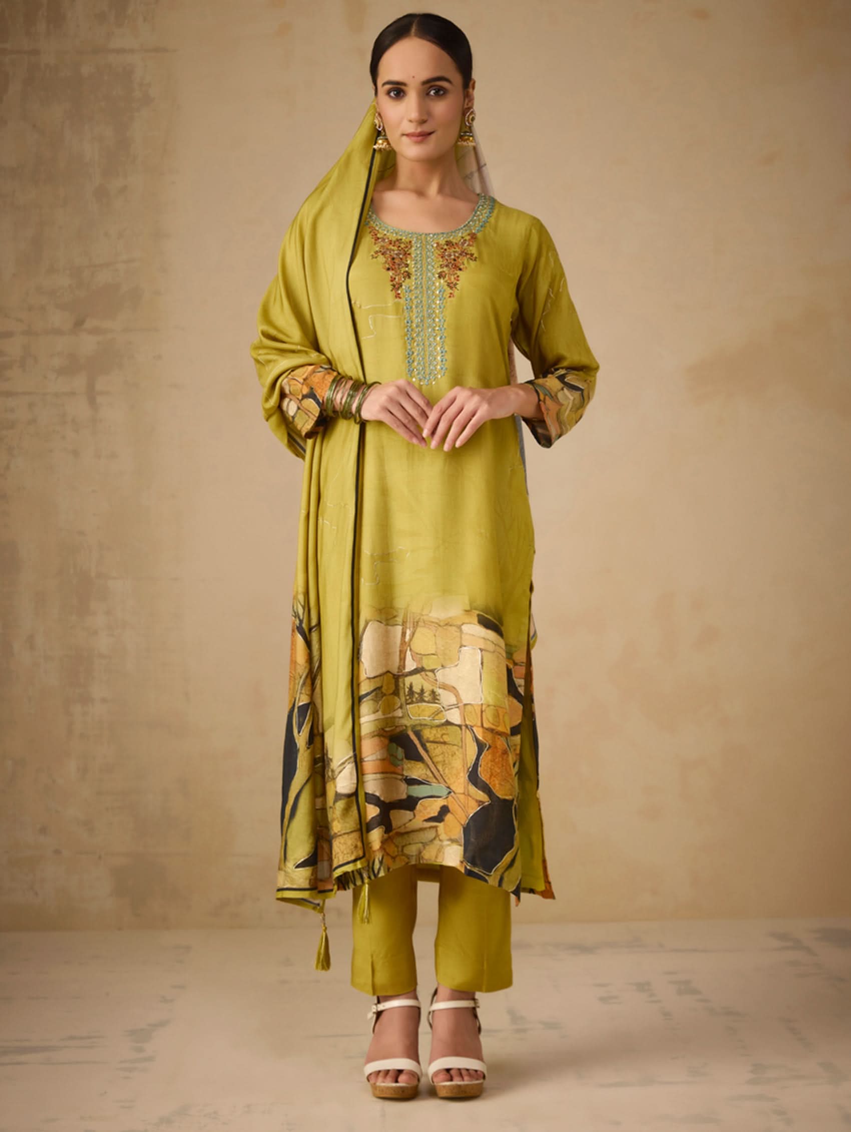 Woman wearing a green traditional outfit with floral patterns on a beige background