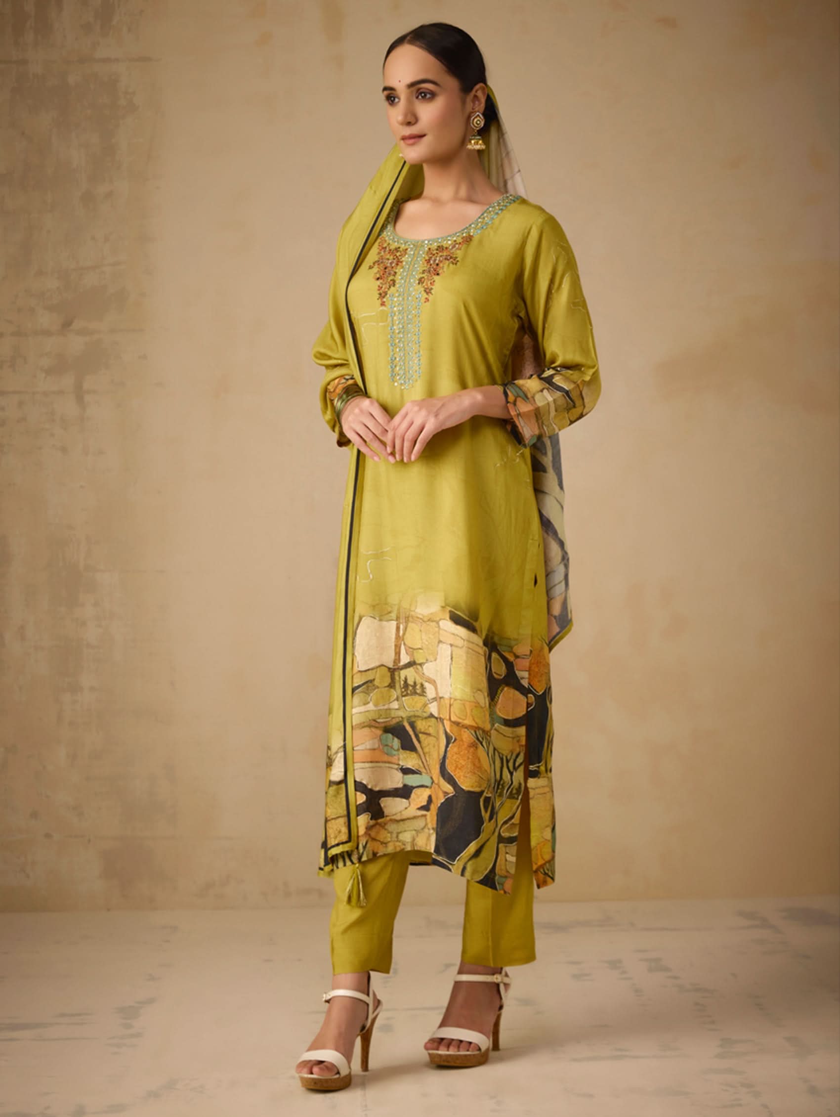 Woman wearing a green traditional outfit with a beige background