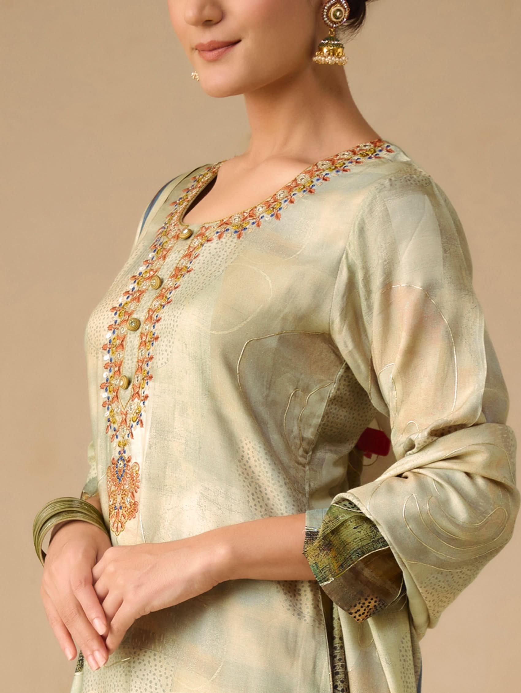 Light green embroidered traditional outfit on a beige background