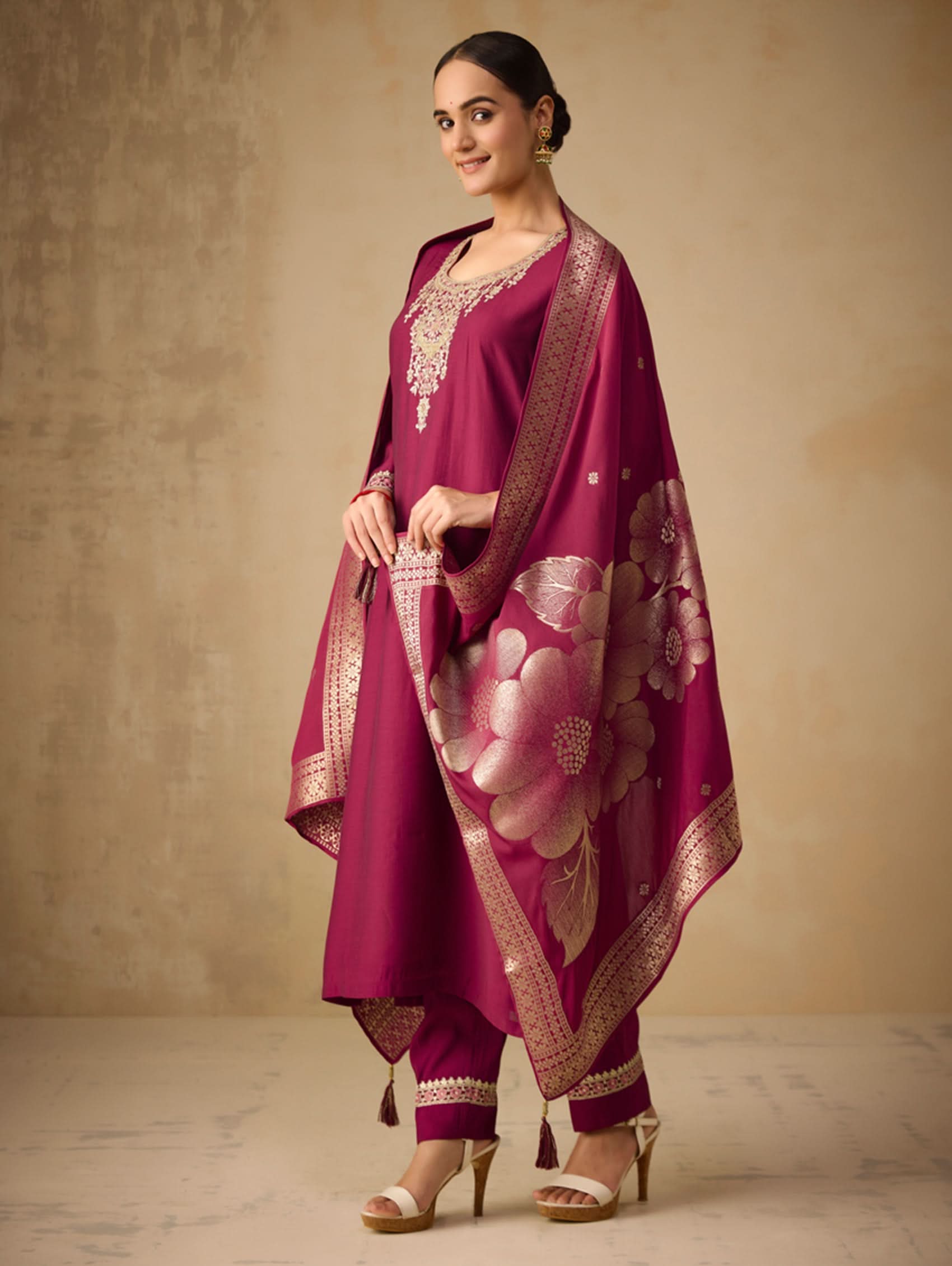 Woman wearing a traditional pink outfit with a floral pattern against a beige background