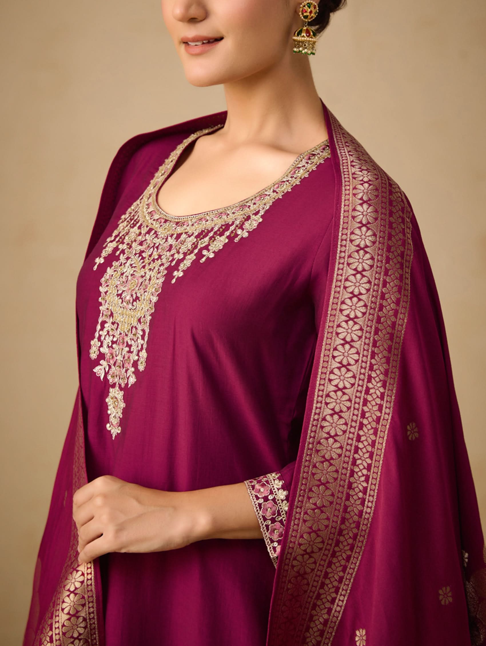 Purple embroidered traditional outfit with a matching dupatta on a beige background