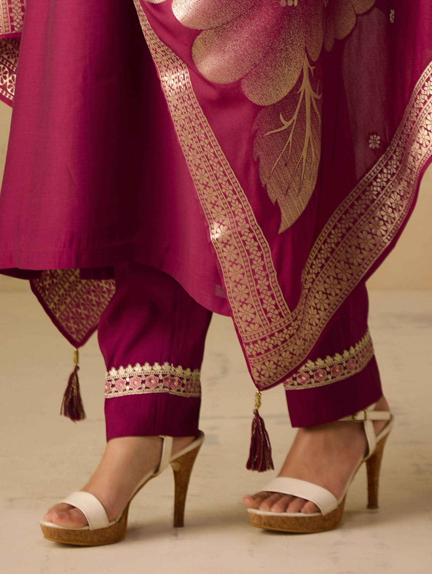 Purple traditional outfit with floral patterns and white high-heeled shoes on a neutral background