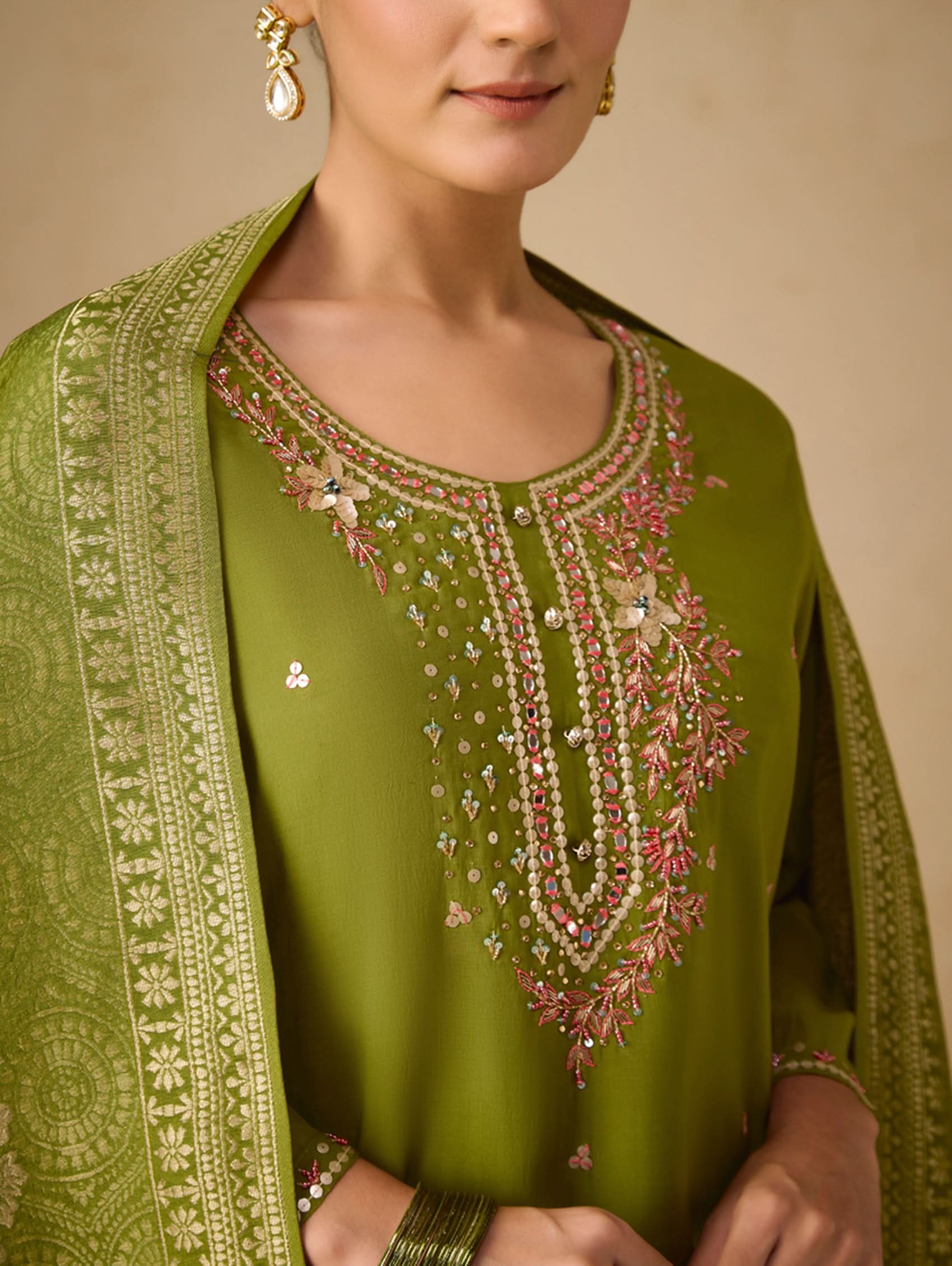 Green embroidered traditional outfit with a beige background