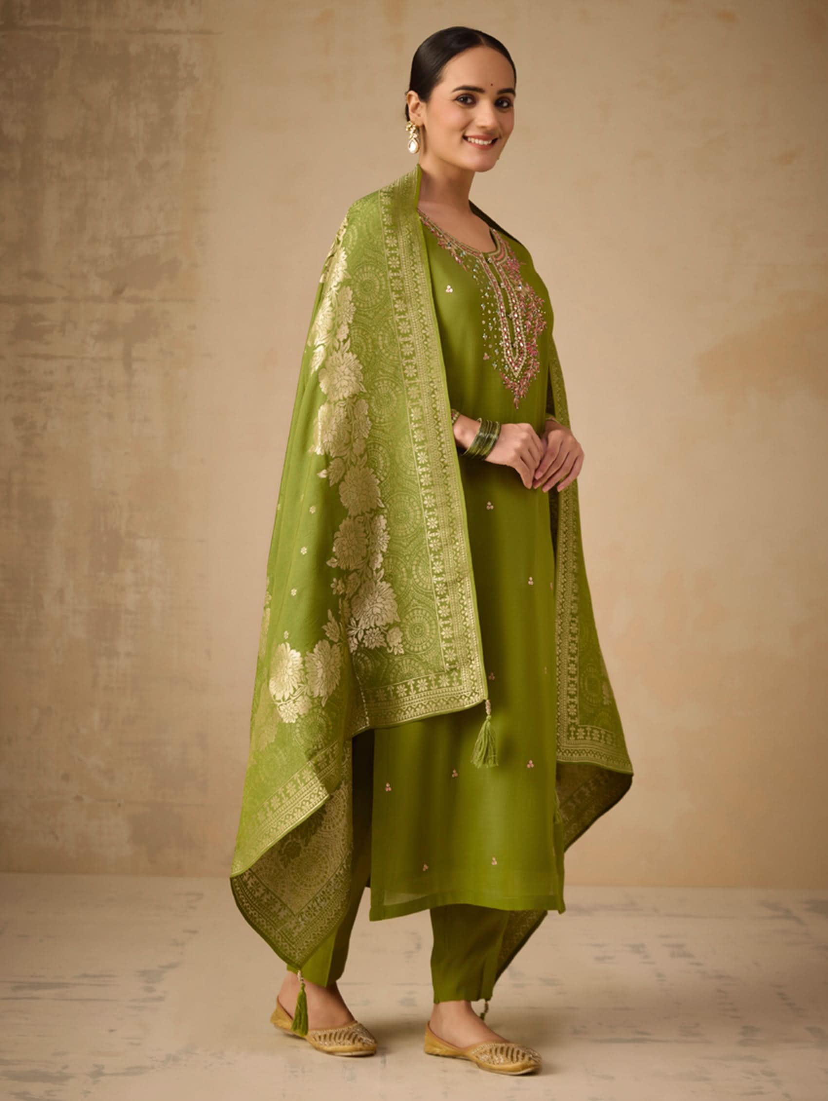 Woman wearing a green traditional outfit with a textured beige background