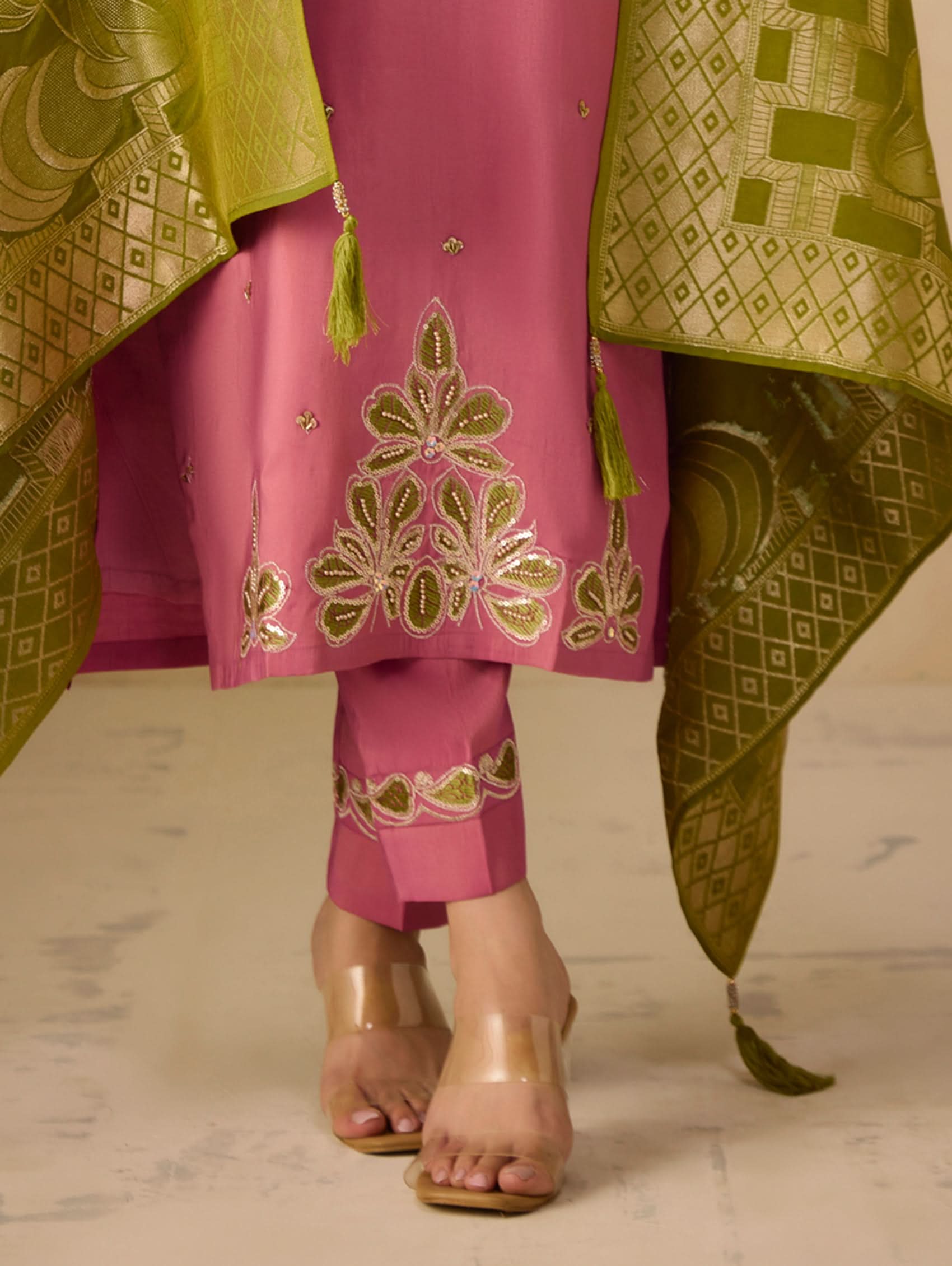 Pink traditional outfit with green embroidery on a neutral background