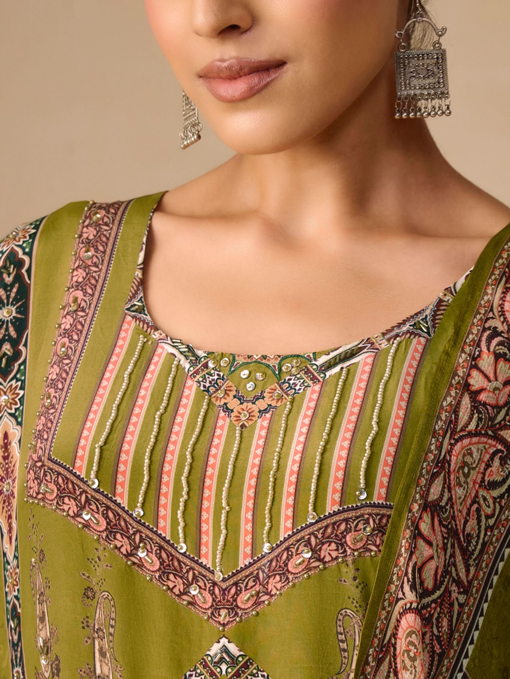 Close-up of a person wearing a green embroidered traditional outfit with intricate patterns.