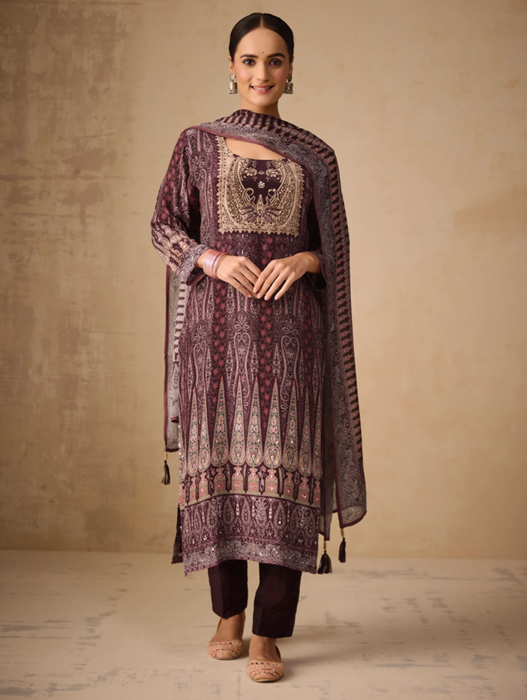 Woman wearing a dark purple embroidered traditional outfit against a beige background