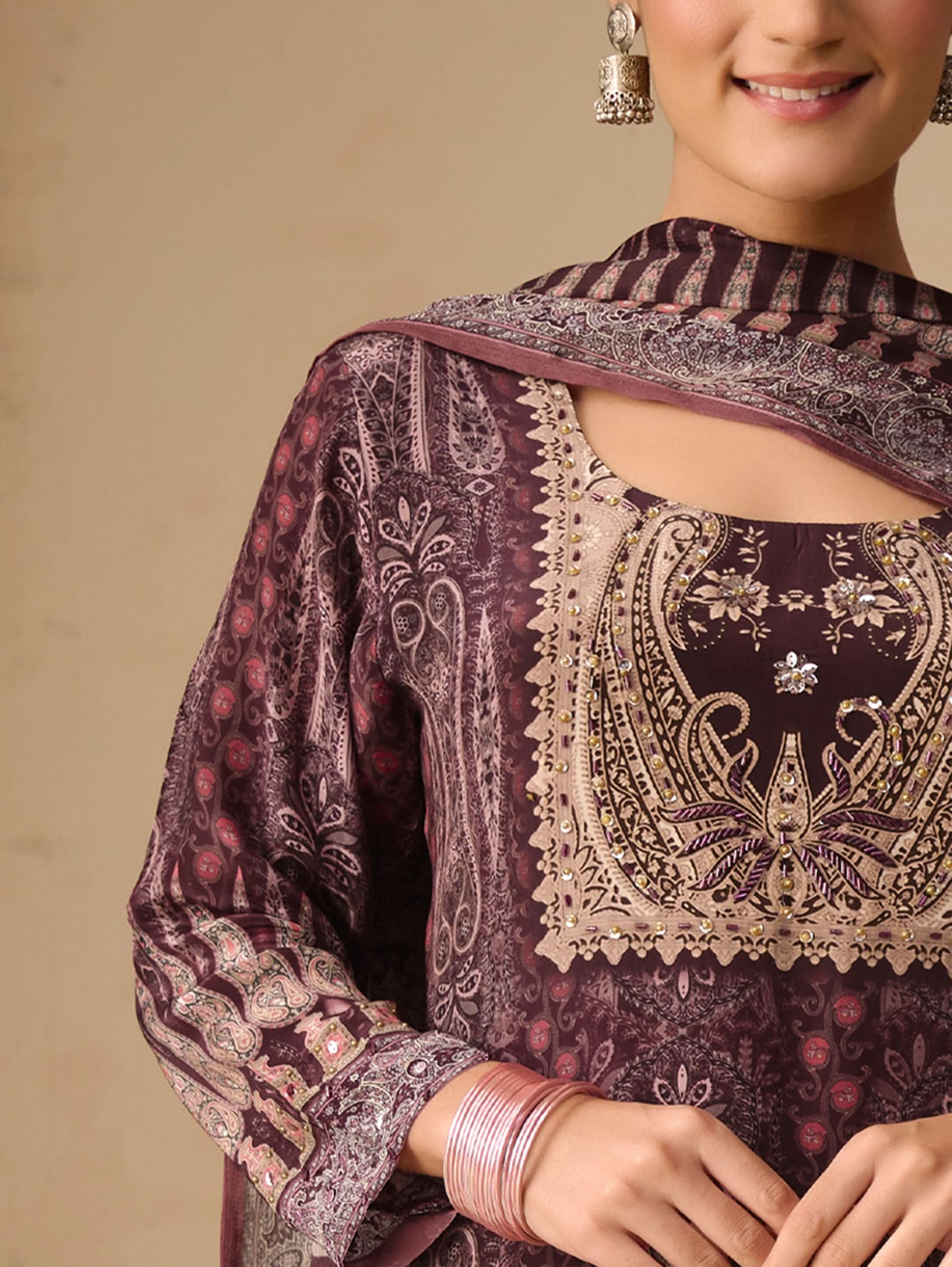 Woman wearing a dark purple embroidered traditional outfit with a beige background