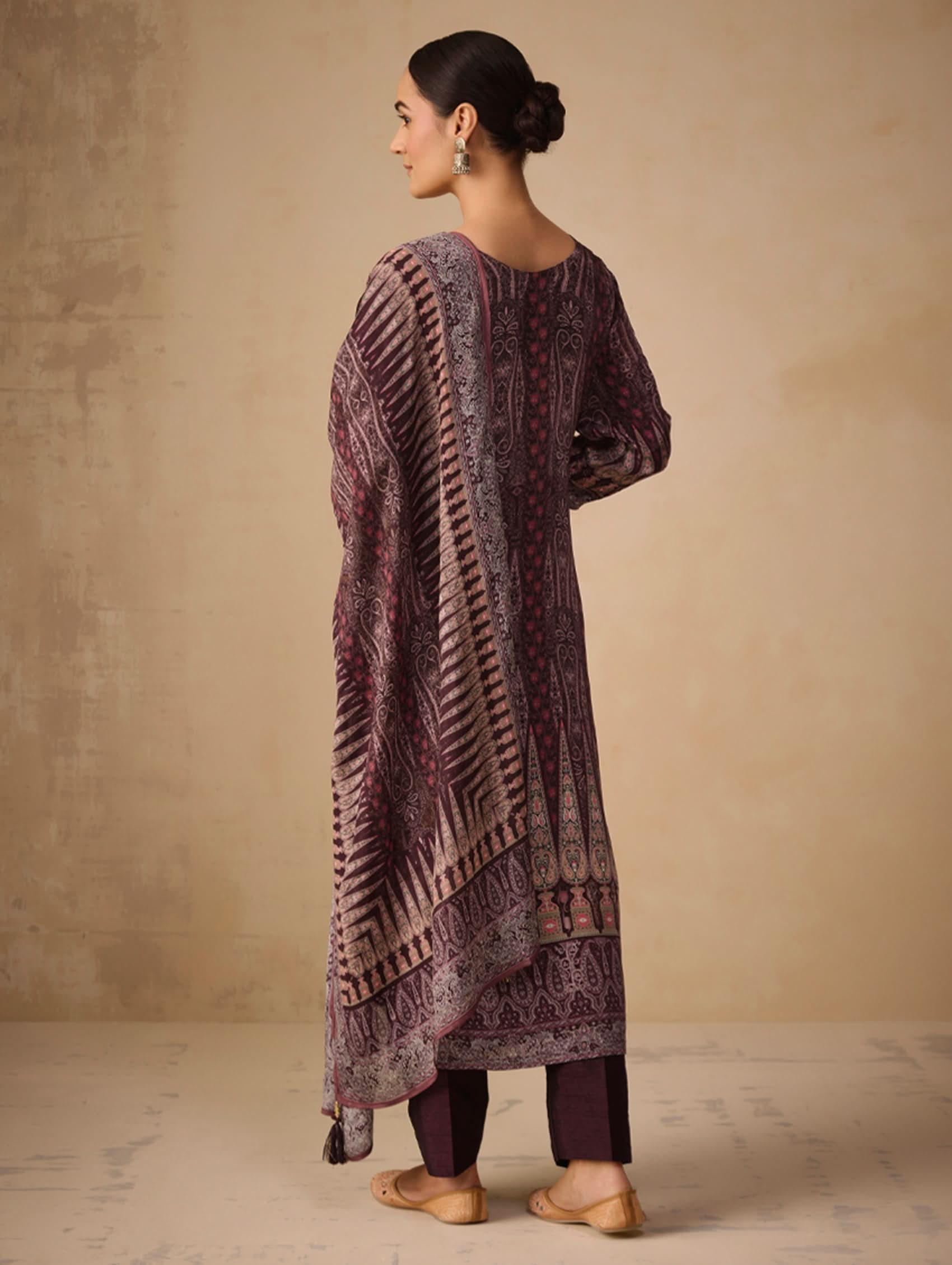 Woman wearing a long, patterned dress against a beige background