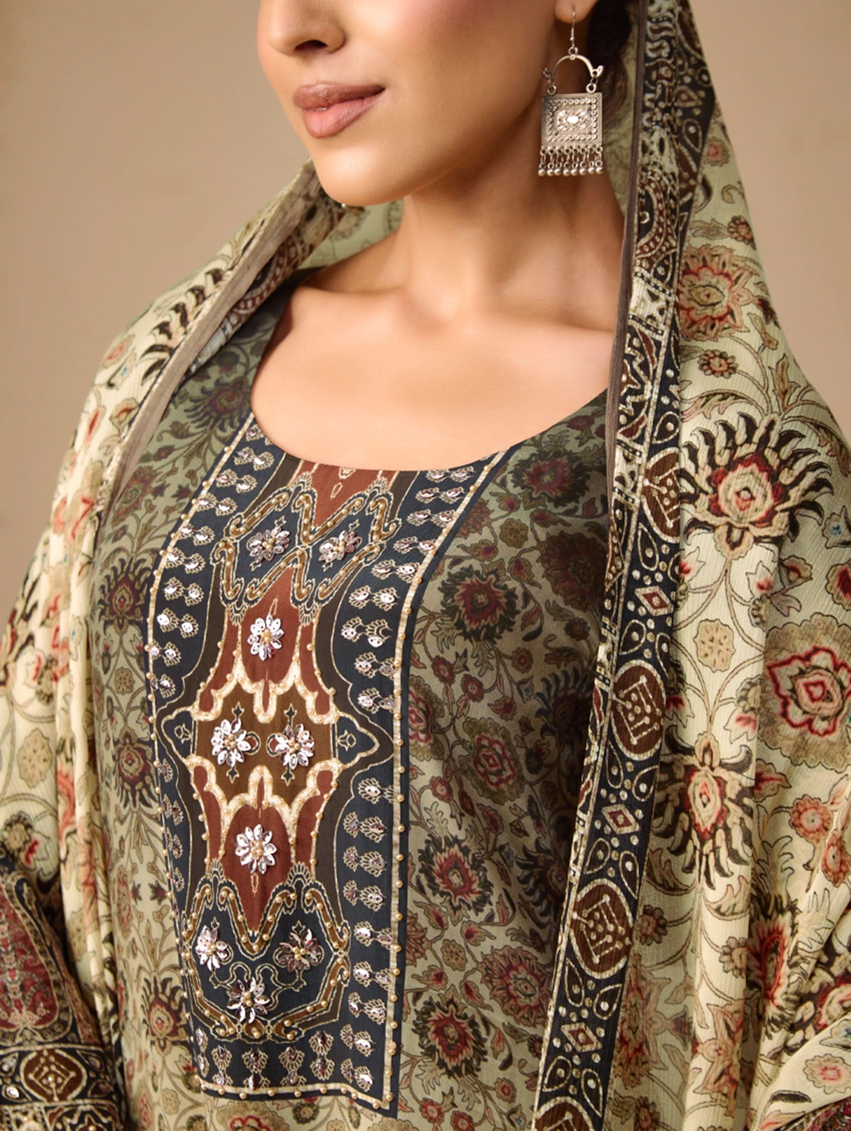Woman wearing a patterned outfit with a scarf, focusing on the intricate design.