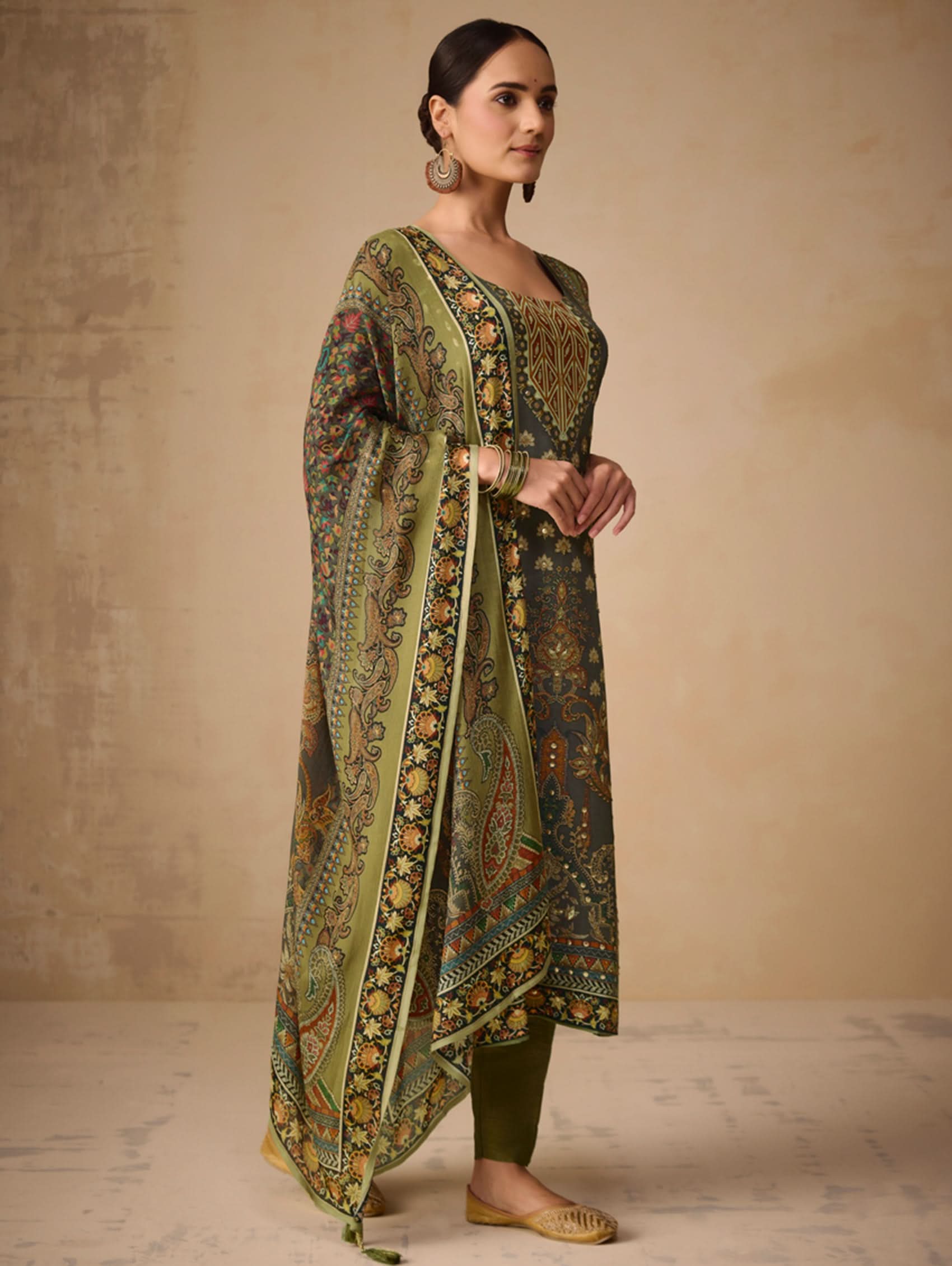 Woman wearing a traditional outfit with a patterned dupatta against a beige background