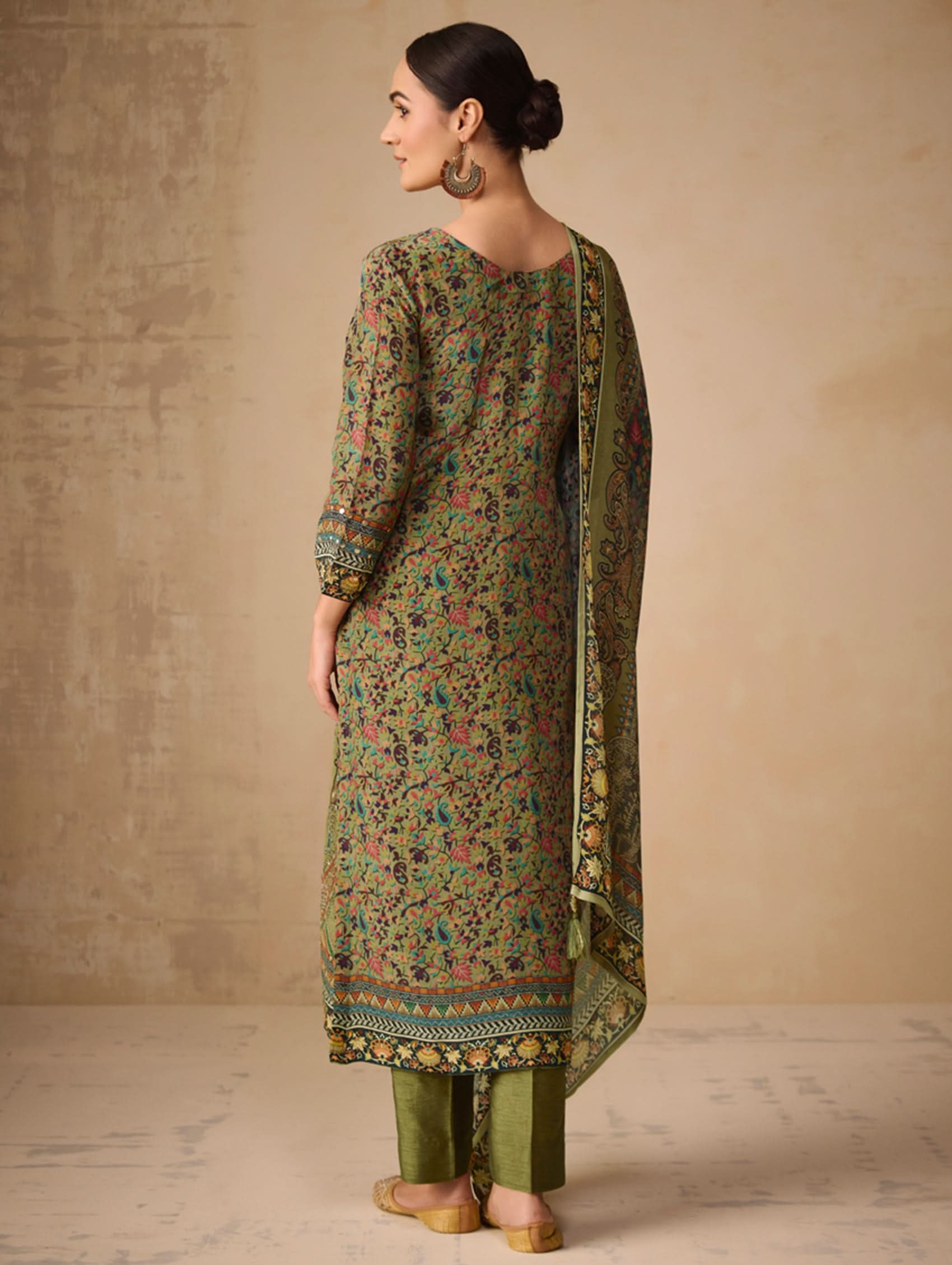 Woman wearing a green floral kurta with matching dupatta against a beige background