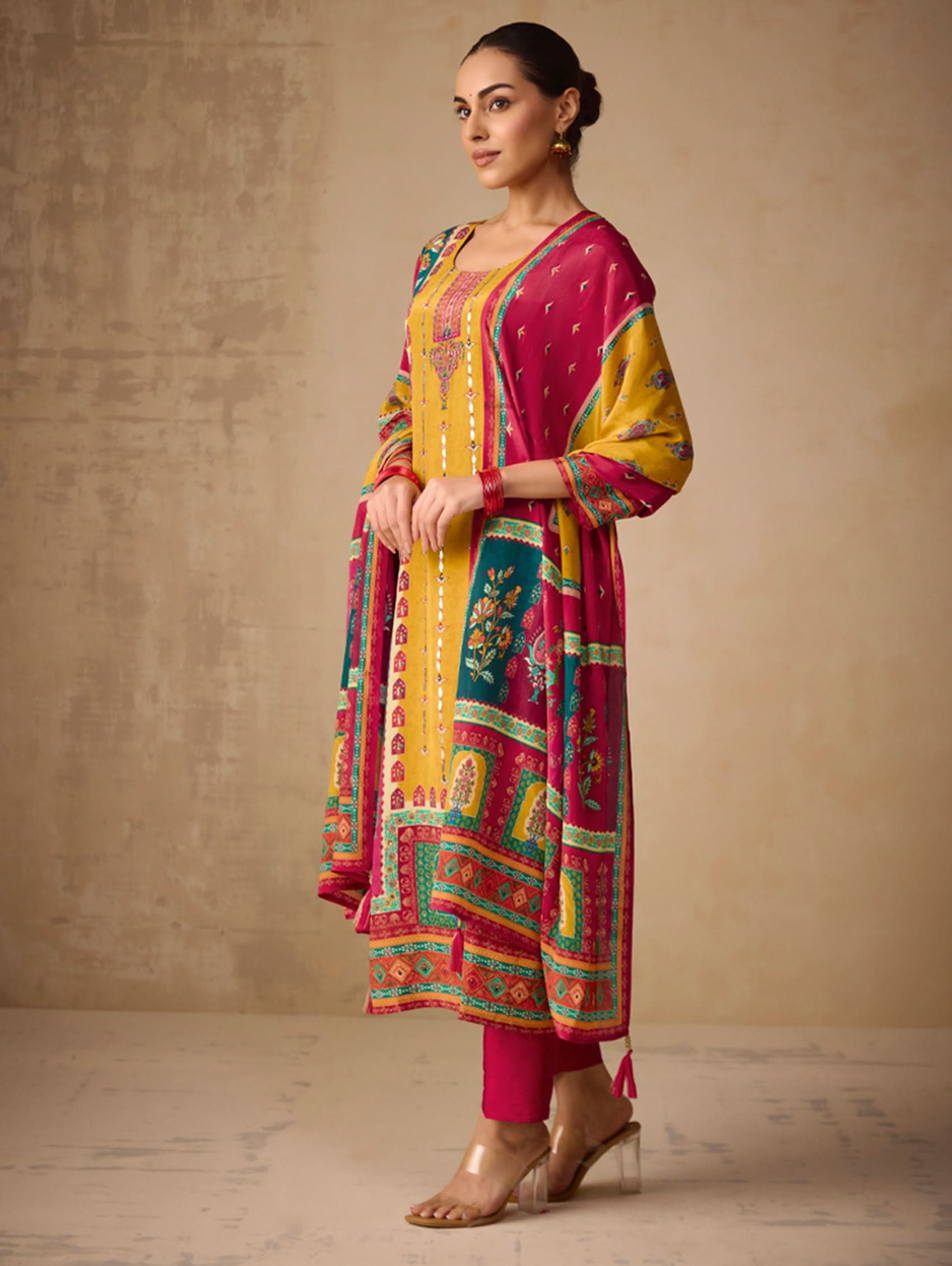 Woman wearing a colorful traditional outfit with a patterned dress against a plain background