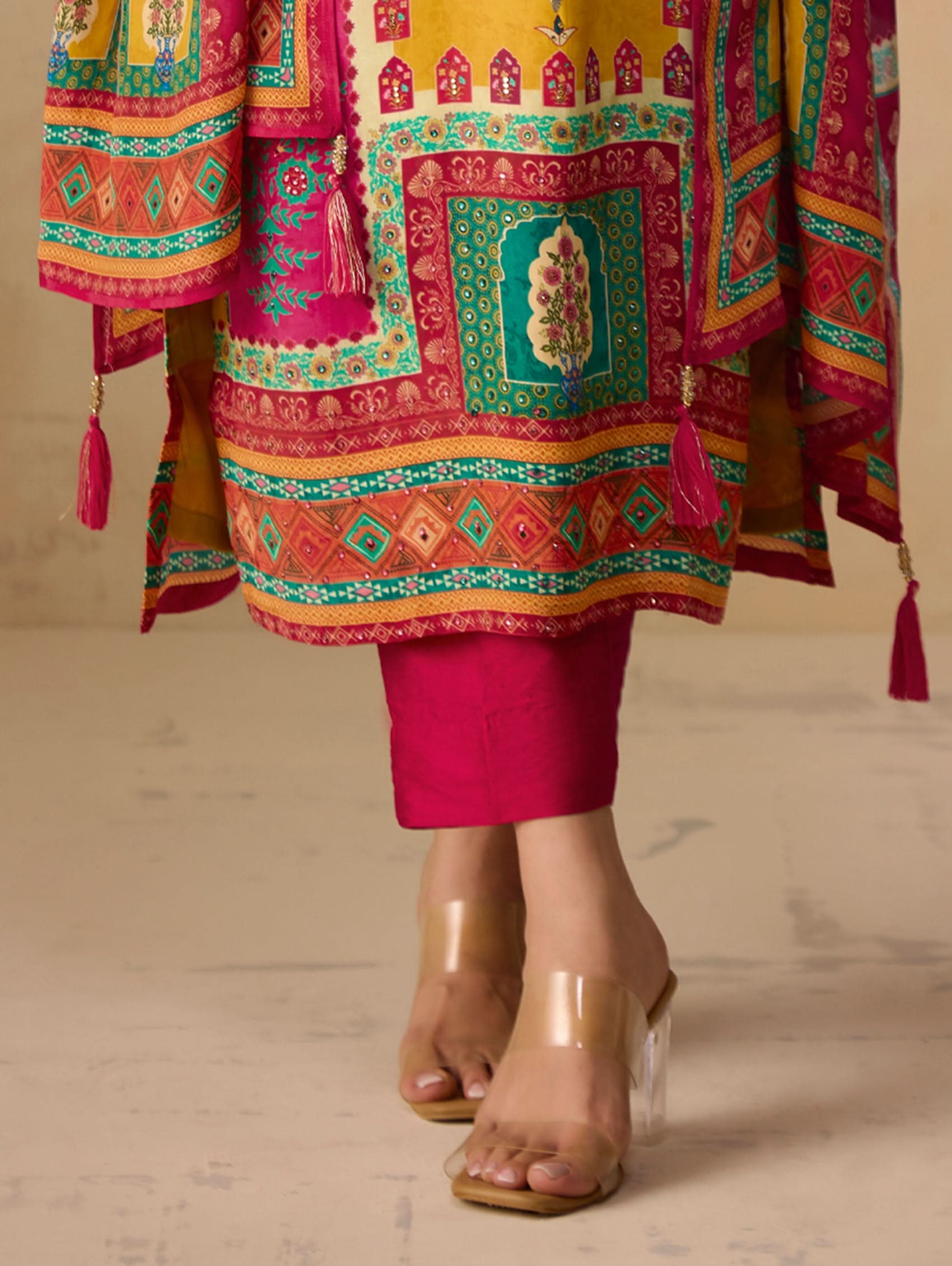 Colorful traditional outfit with a patterned top and pink pants on a neutral background