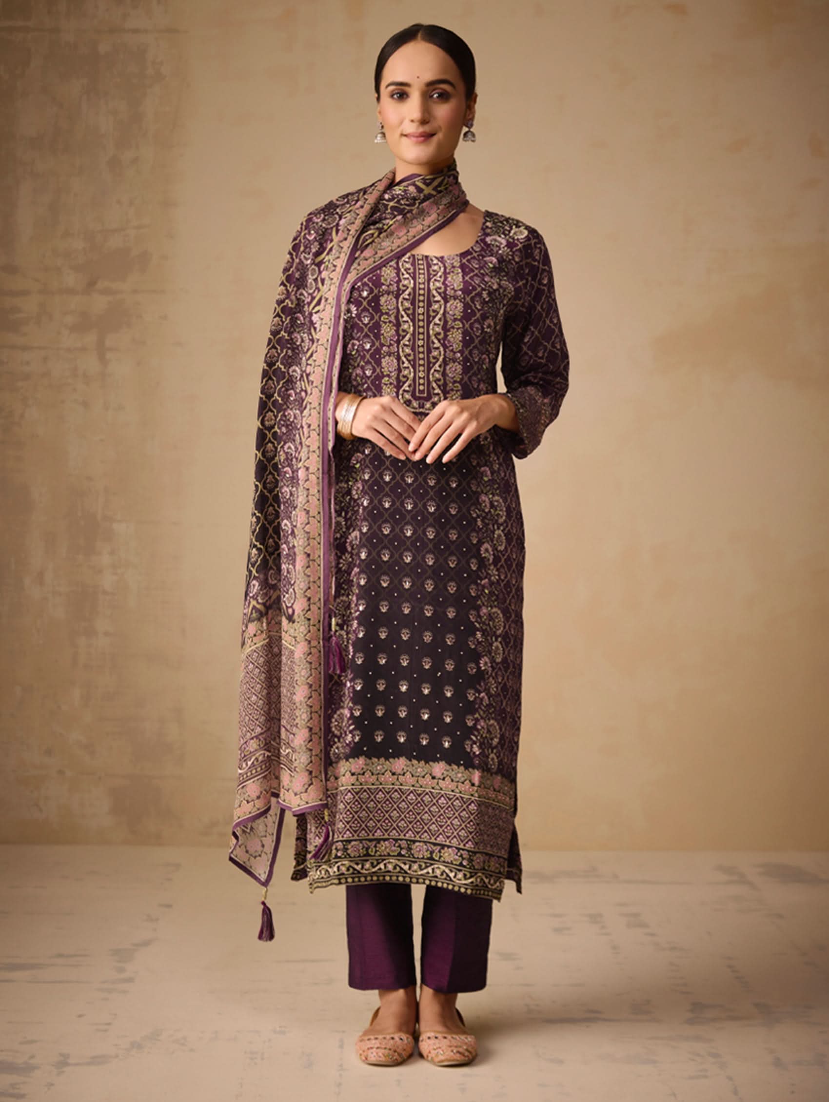 Woman wearing a traditional outfit with a patterned shawl against a beige background