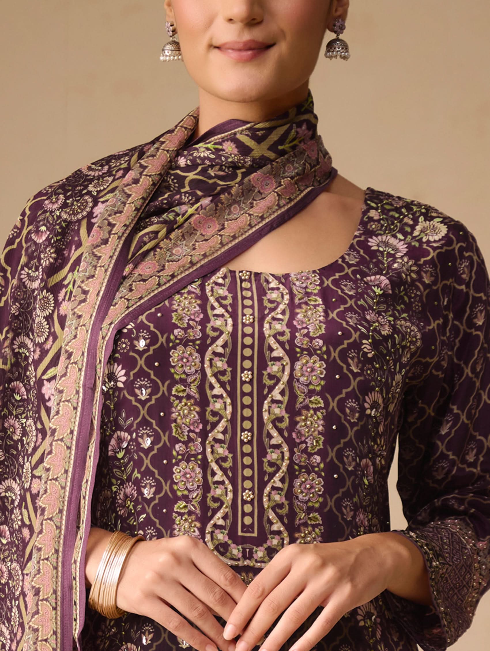 Woman wearing a traditional embroidered outfit with a focus on purple and gold patterns.