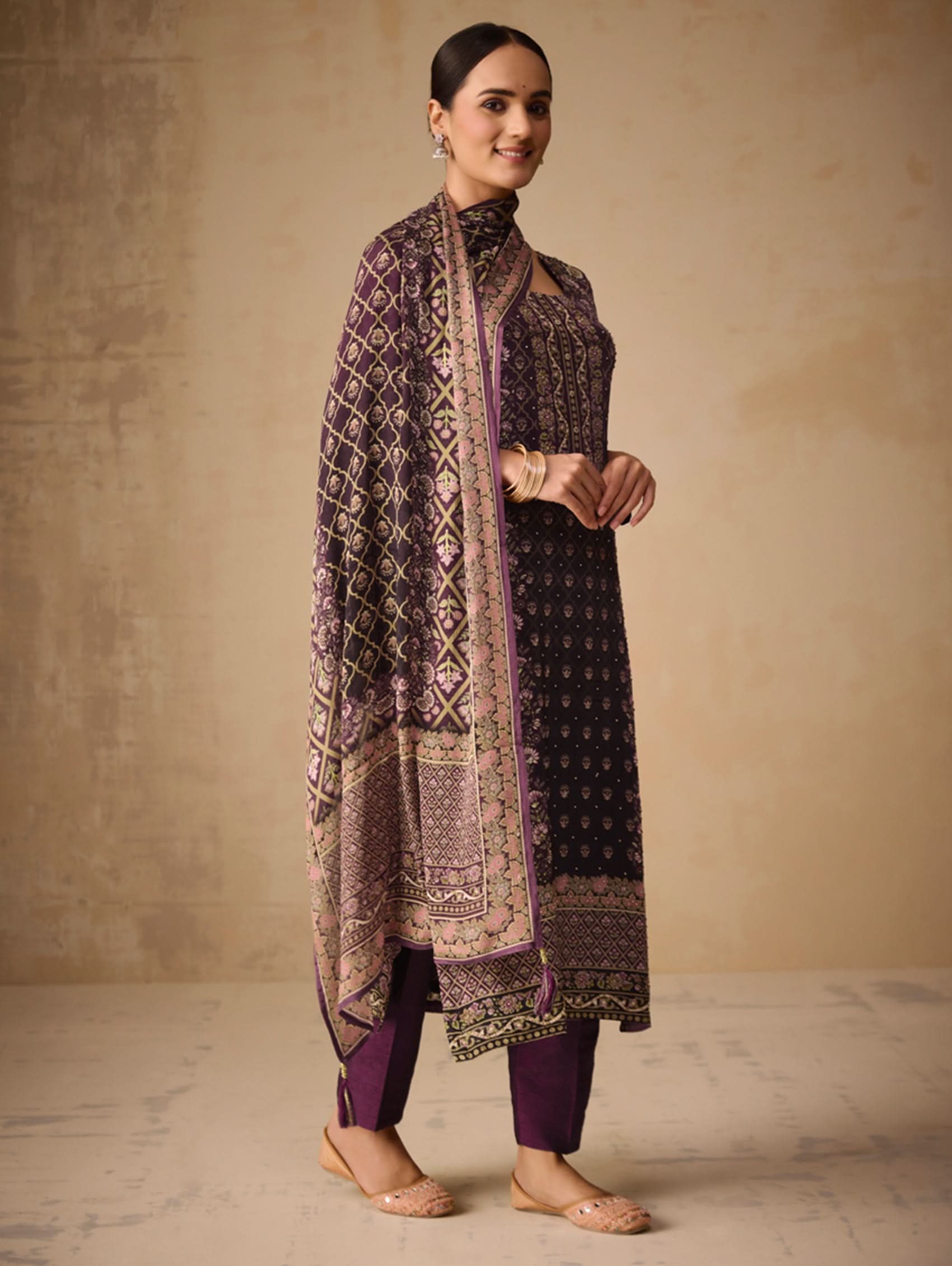 Woman wearing a traditional outfit with a patterned shawl against a beige background