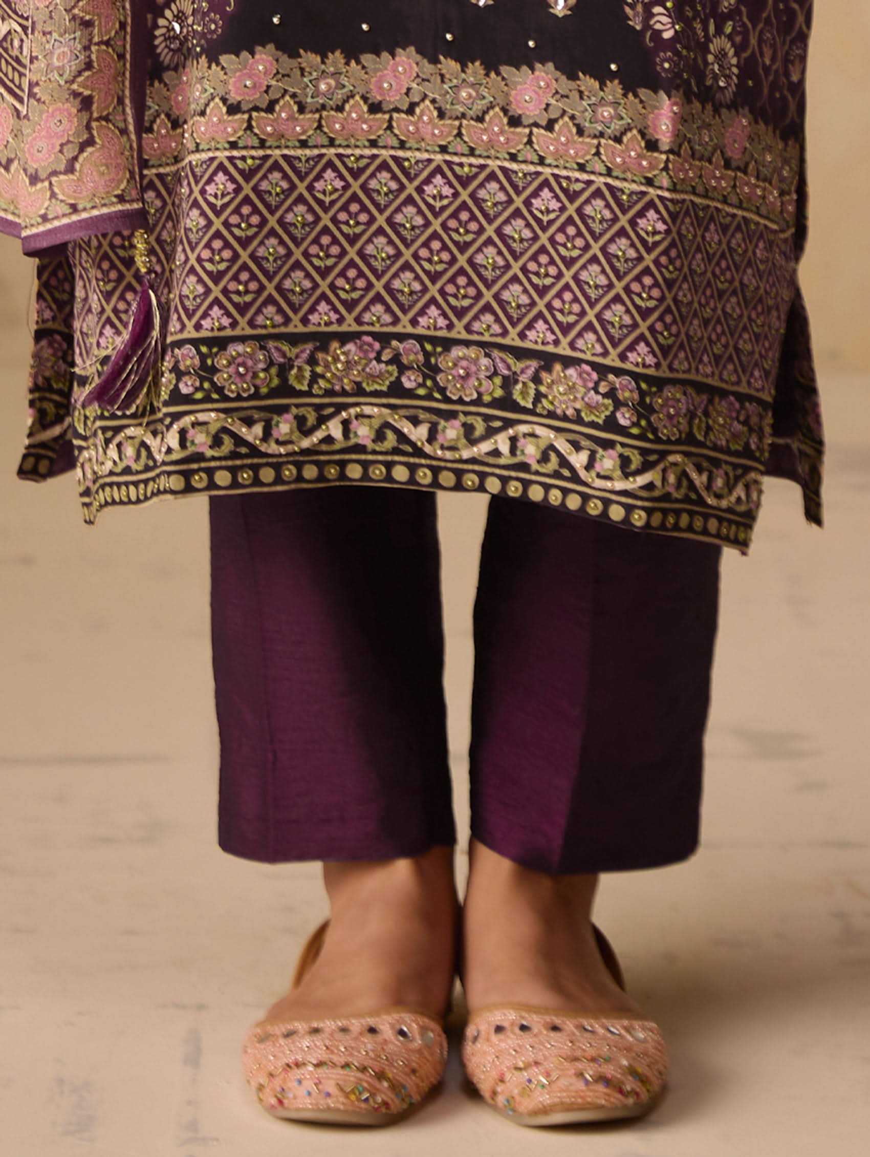 Traditional outfit with embroidered top and purple pants on a neutral background