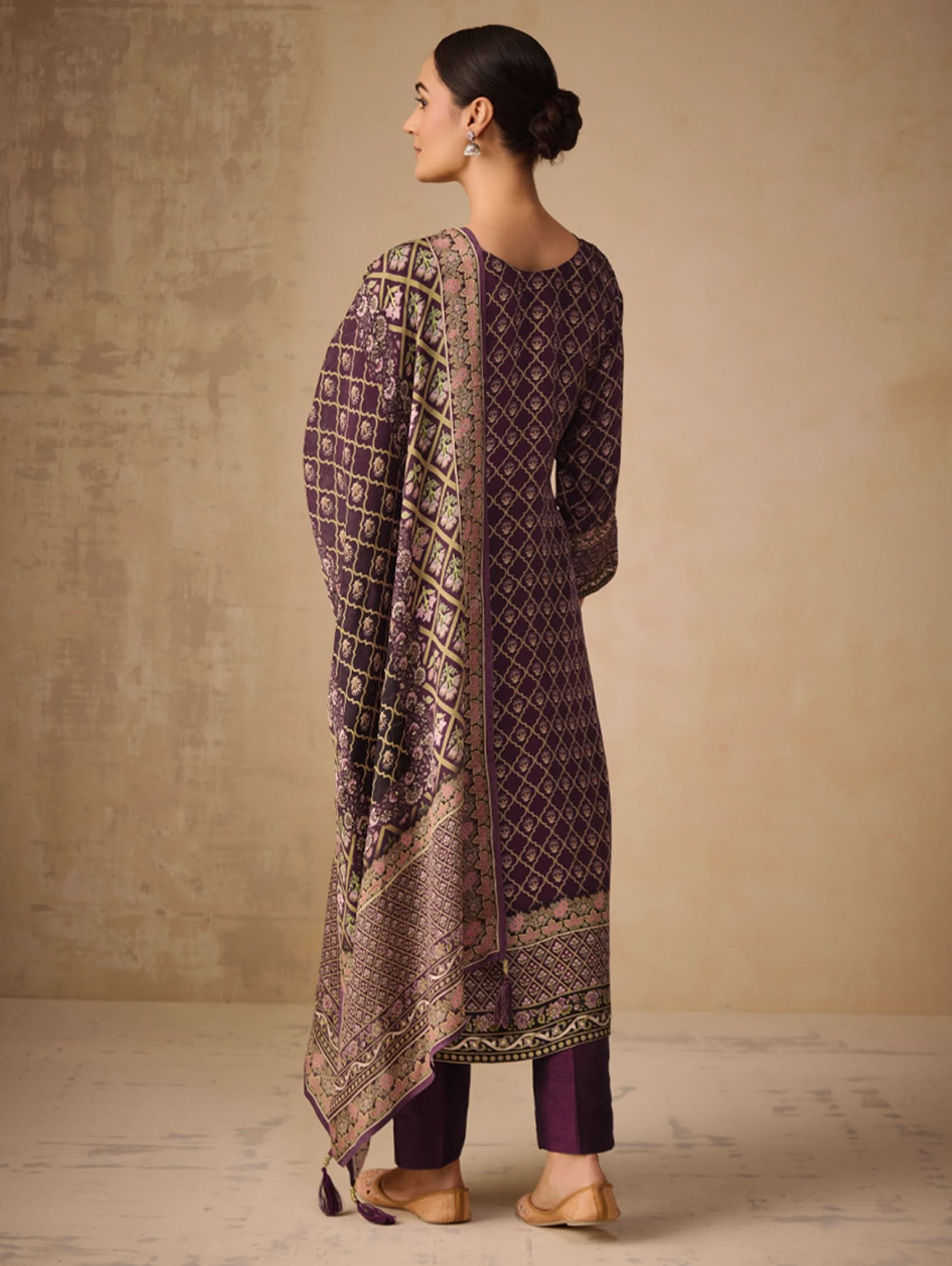 Woman wearing a patterned purple outfit against a beige wall