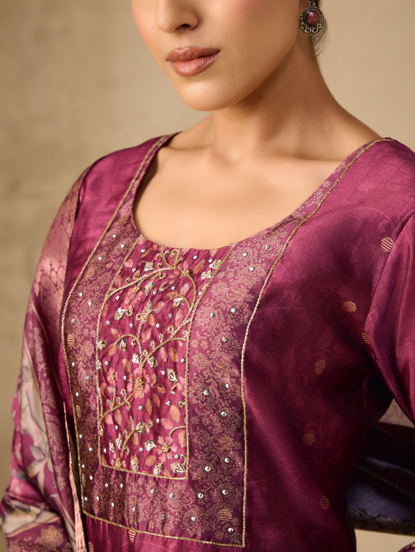 Close-up of a person wearing a purple embroidered traditional outfit with a neutral background