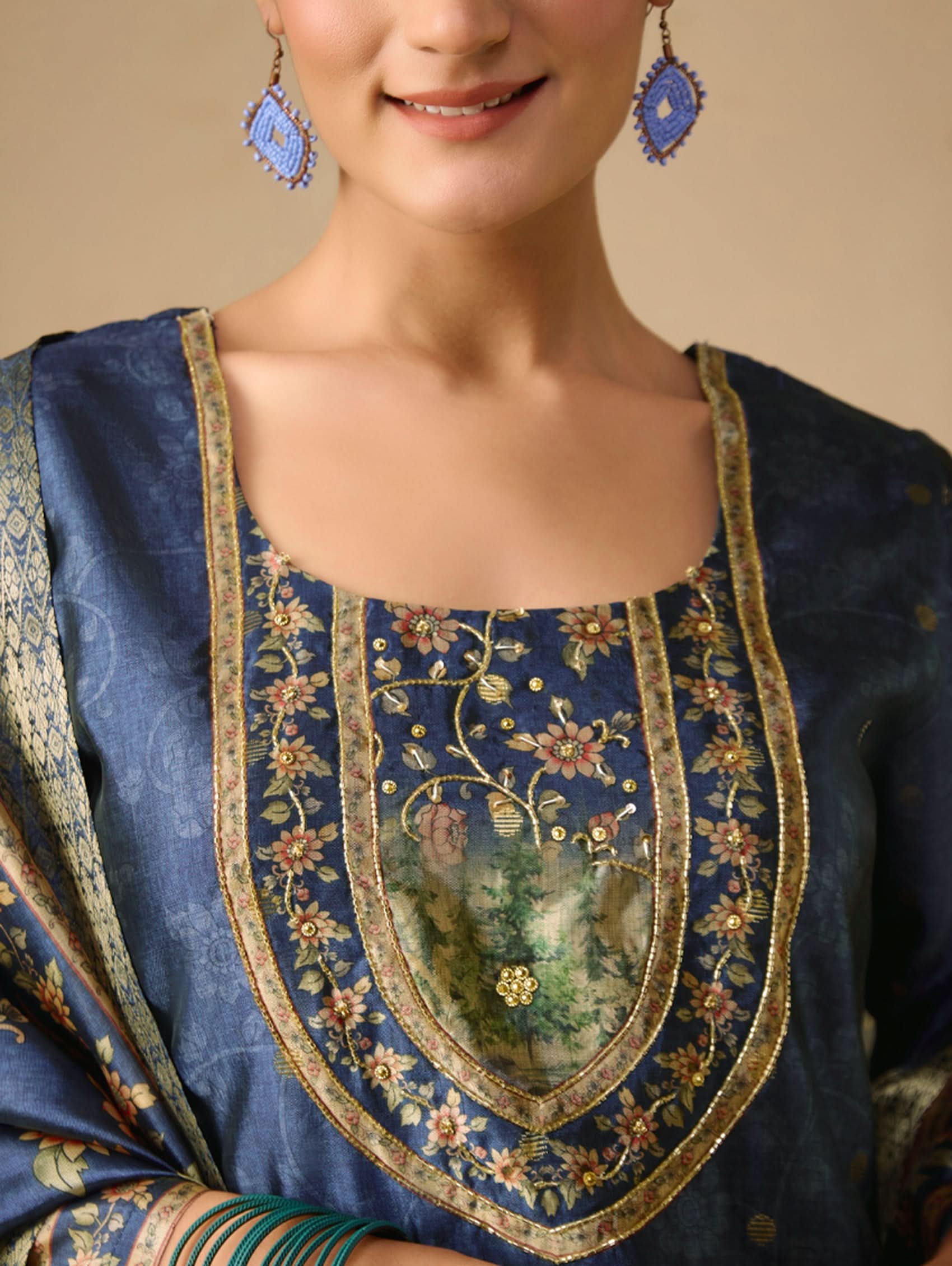Close-up of a person wearing a blue embroidered traditional outfit with gold detailing.