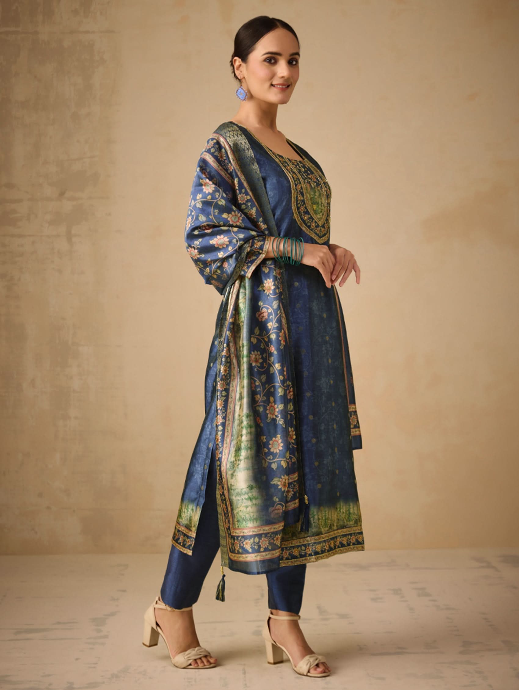 Woman wearing a traditional blue and green outfit with a beige background