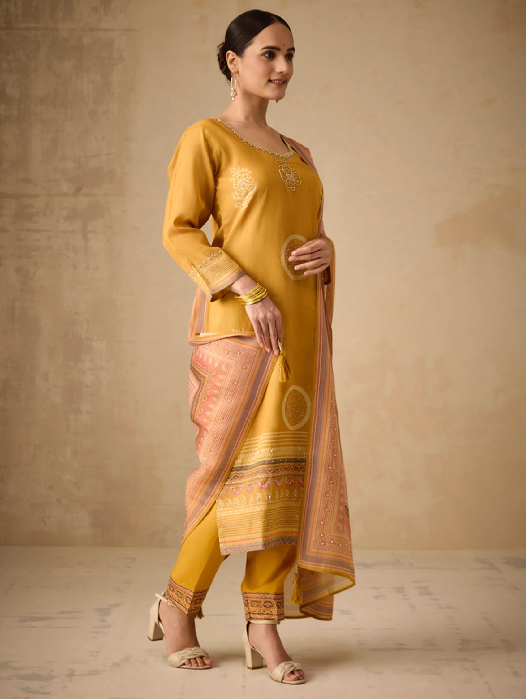 Woman wearing a mustard yellow traditional outfit with a beige background