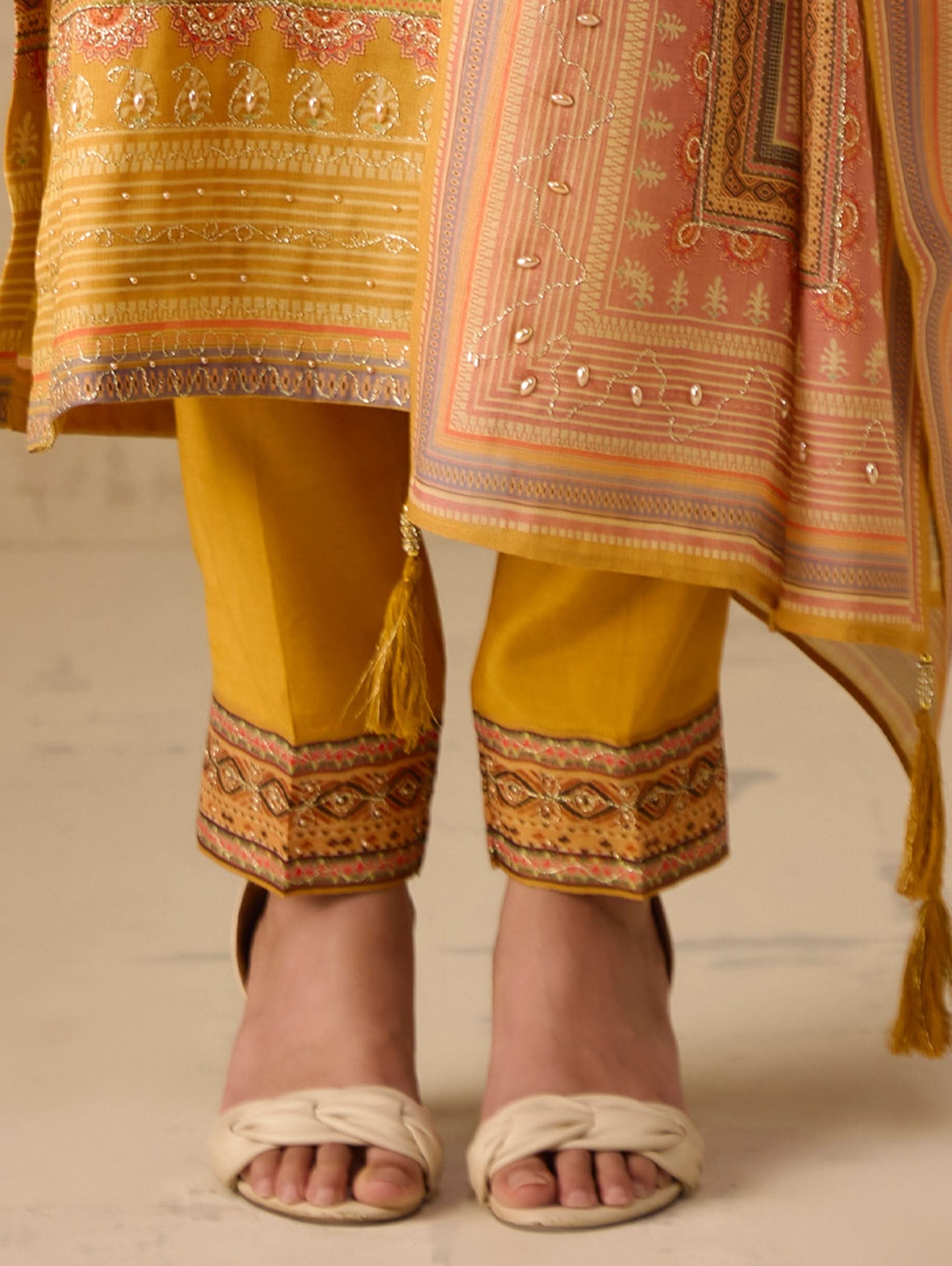 Traditional outfit with yellow pants and patterned top on a neutral background