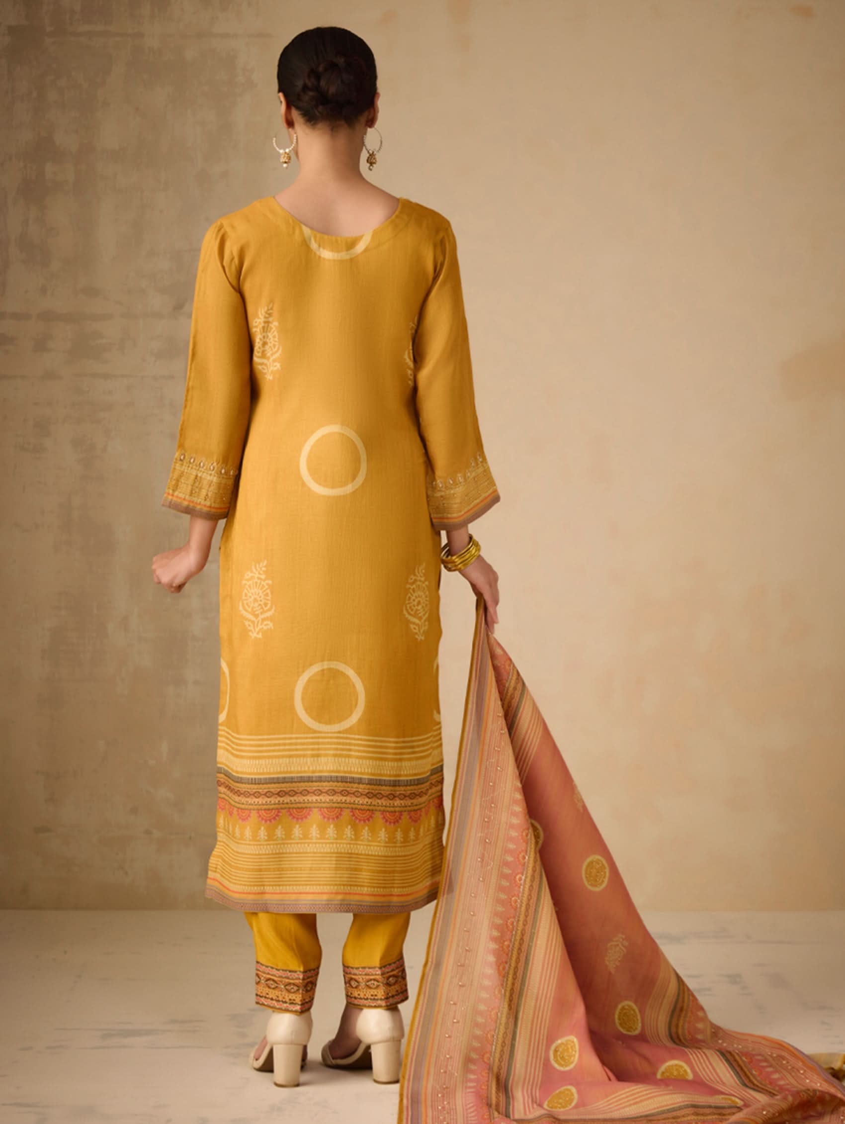 Woman wearing a mustard yellow kurta with a beige background