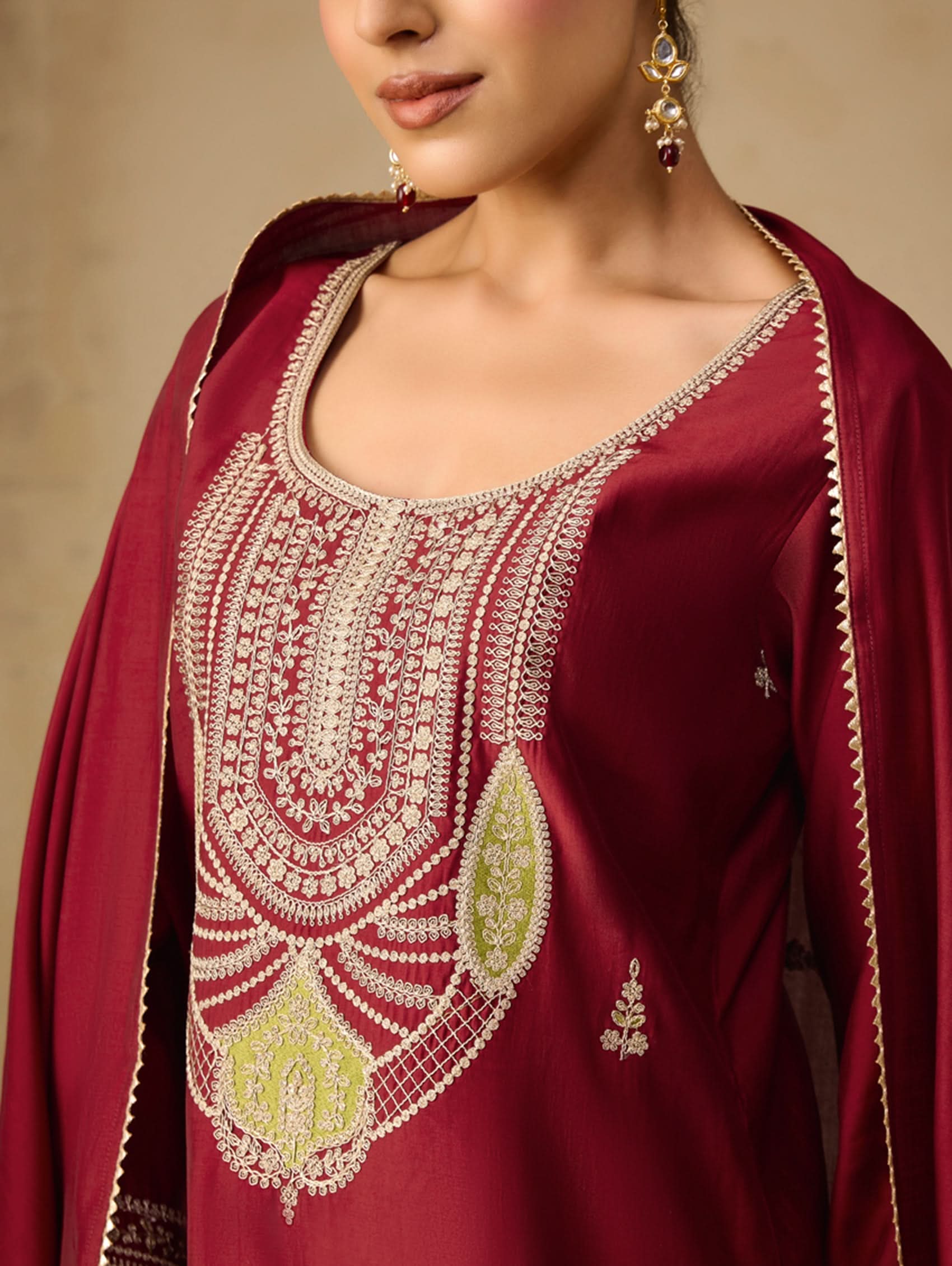 Maroon traditional outfit with intricate white embroidery on a neutral background