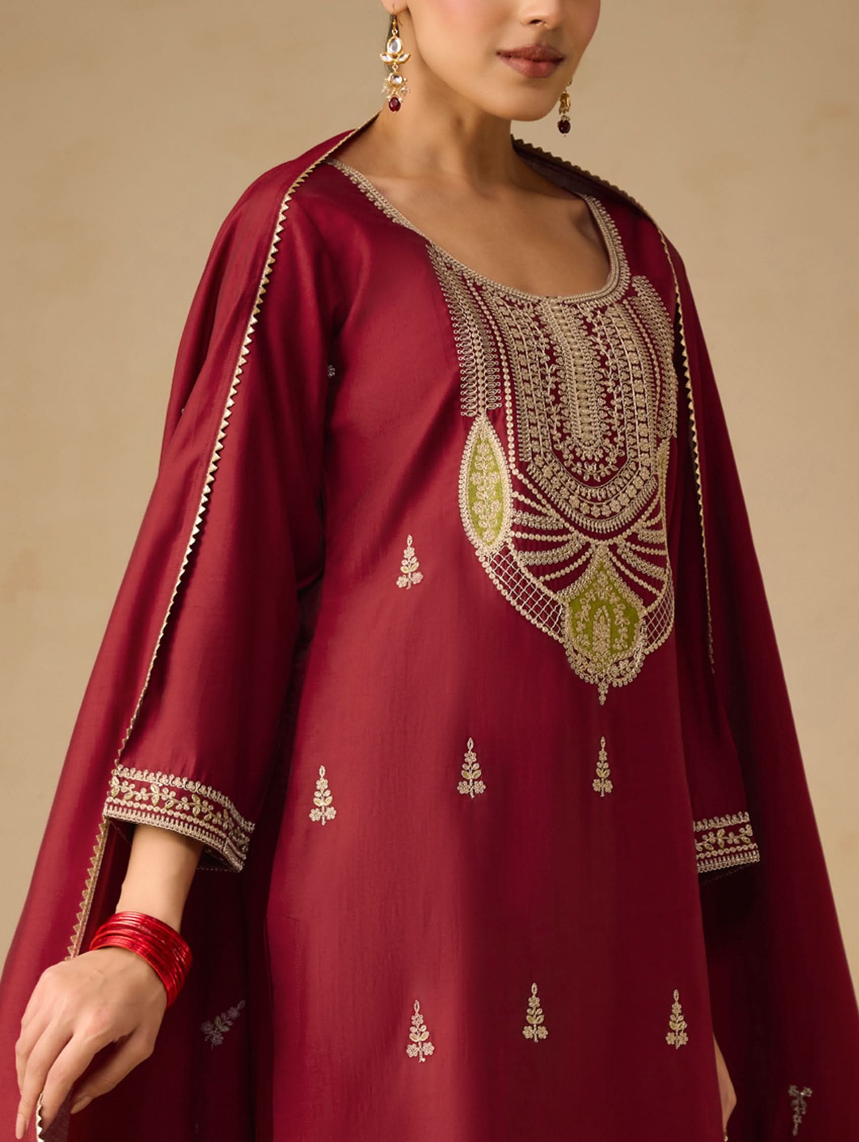 Red embroidered traditional outfit with gold detailing on a beige background