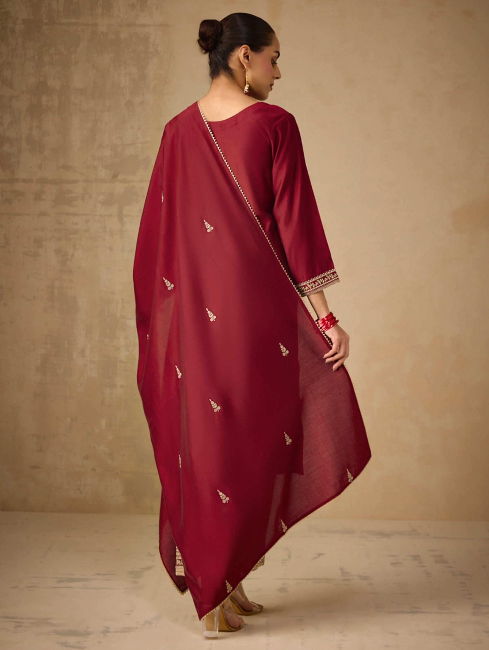 Woman wearing a maroon traditional outfit with a beige background