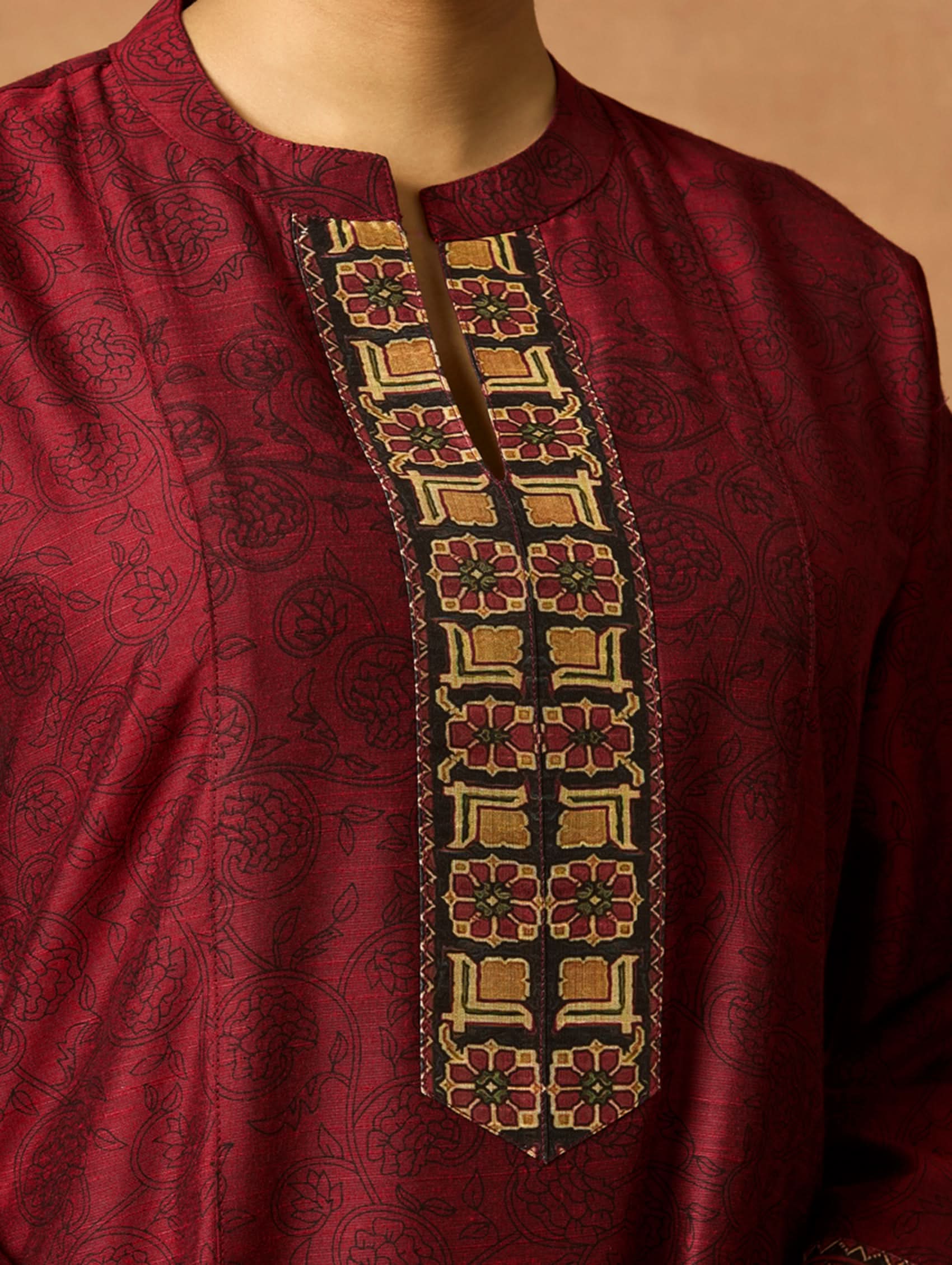 Maroon kurta with intricate embroidery on a beige background