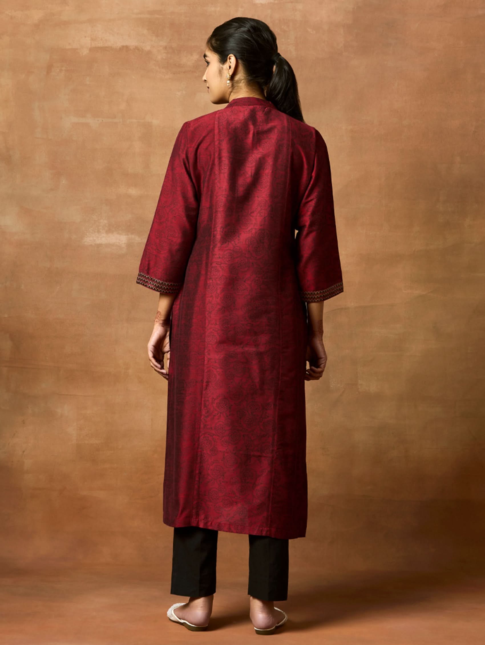 Woman wearing a maroon kurta against a brown background
