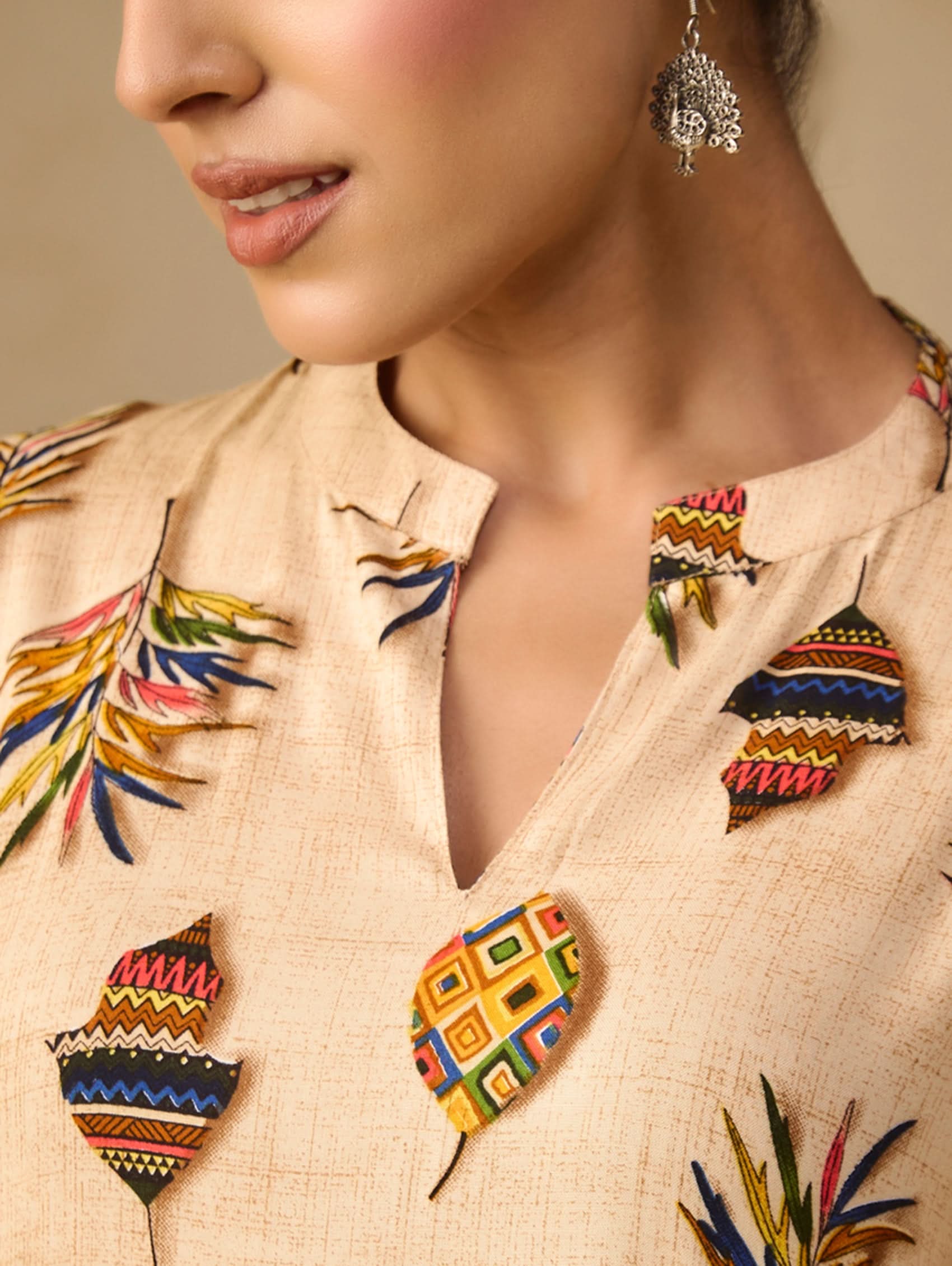 Close-up of a person wearing a beige embroidered outfit with colorful patterns.