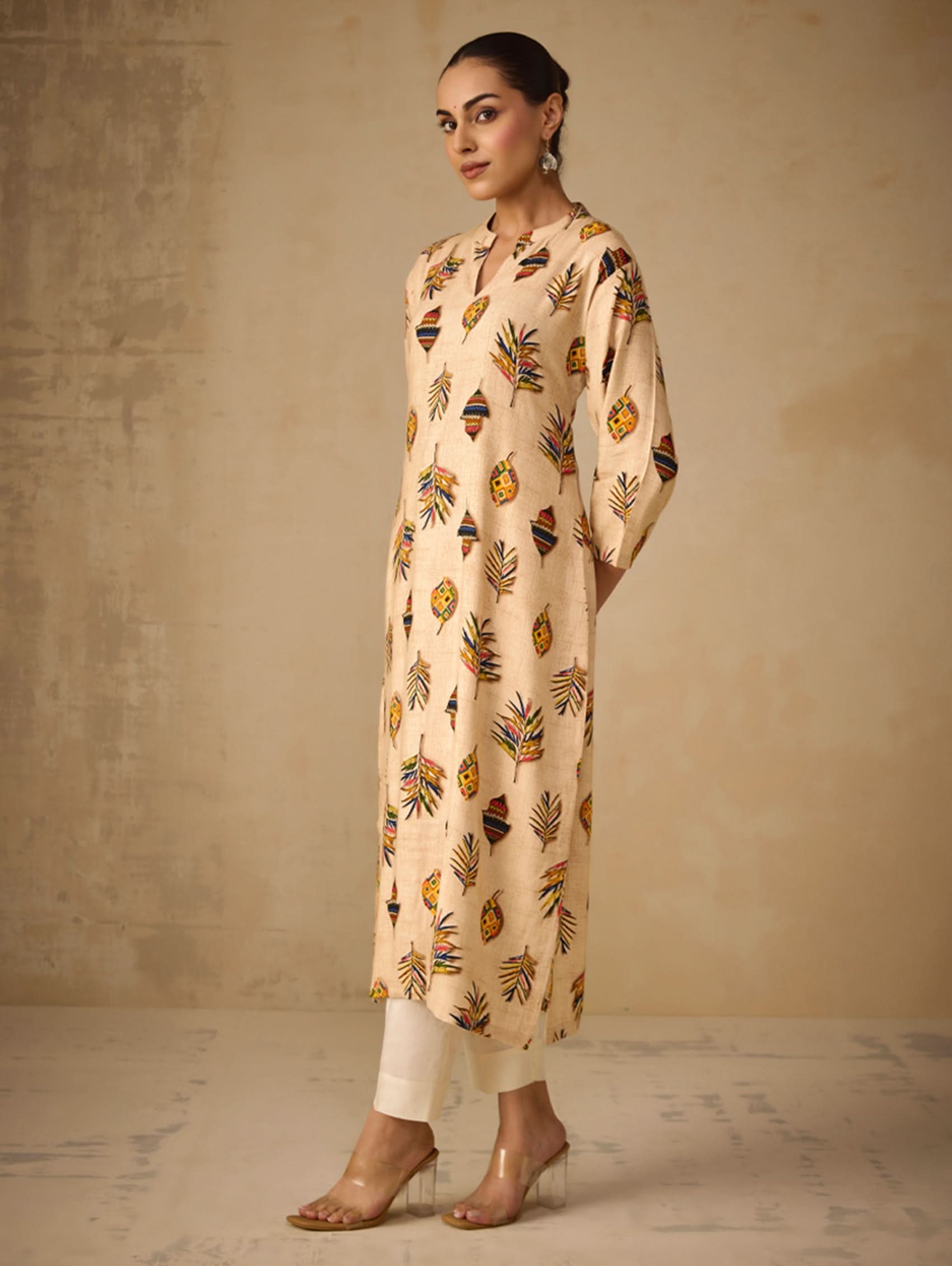 Woman wearing a beige kurta with floral patterns against a neutral background