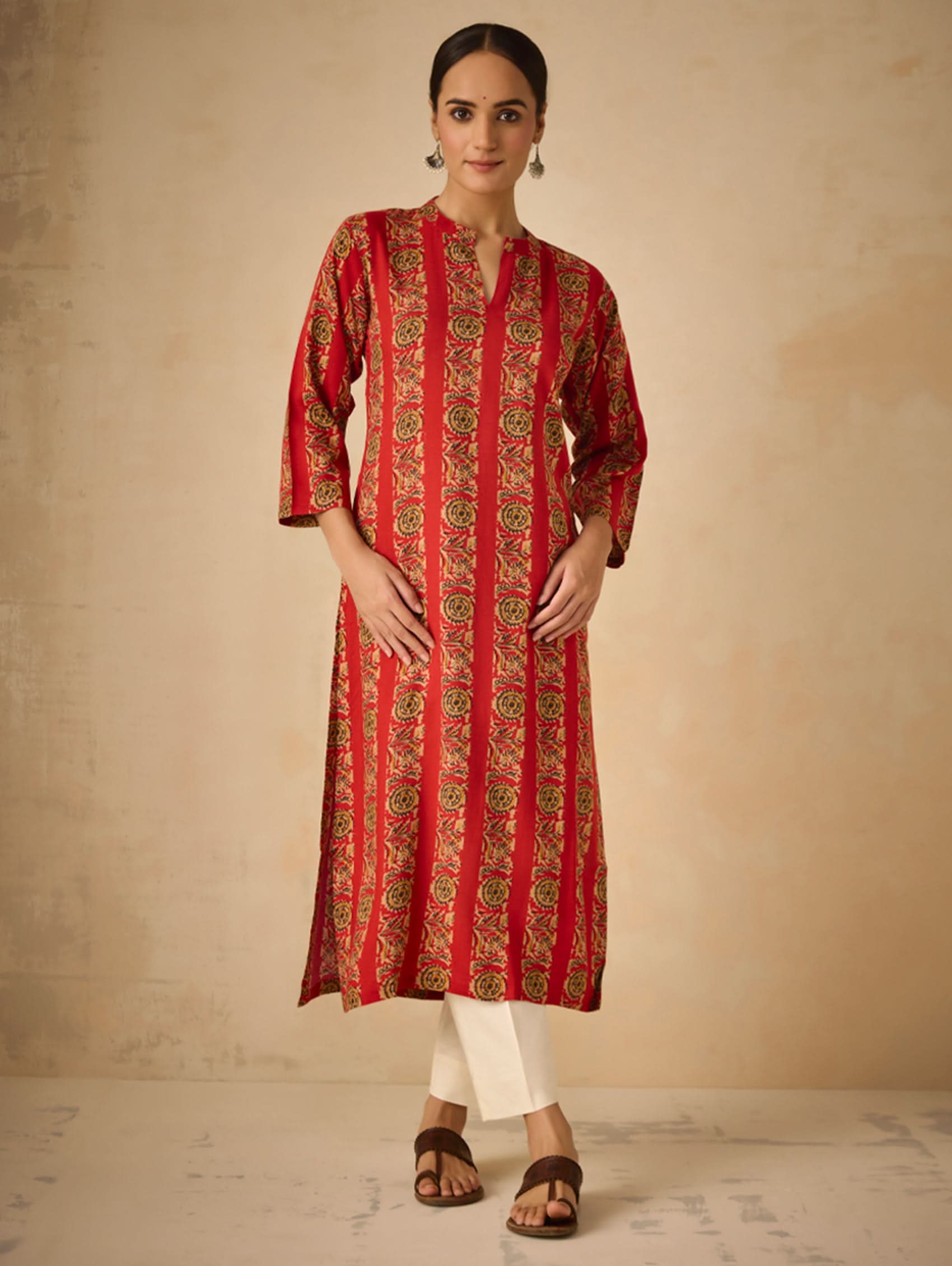 Woman wearing a red patterned kurta against a beige background