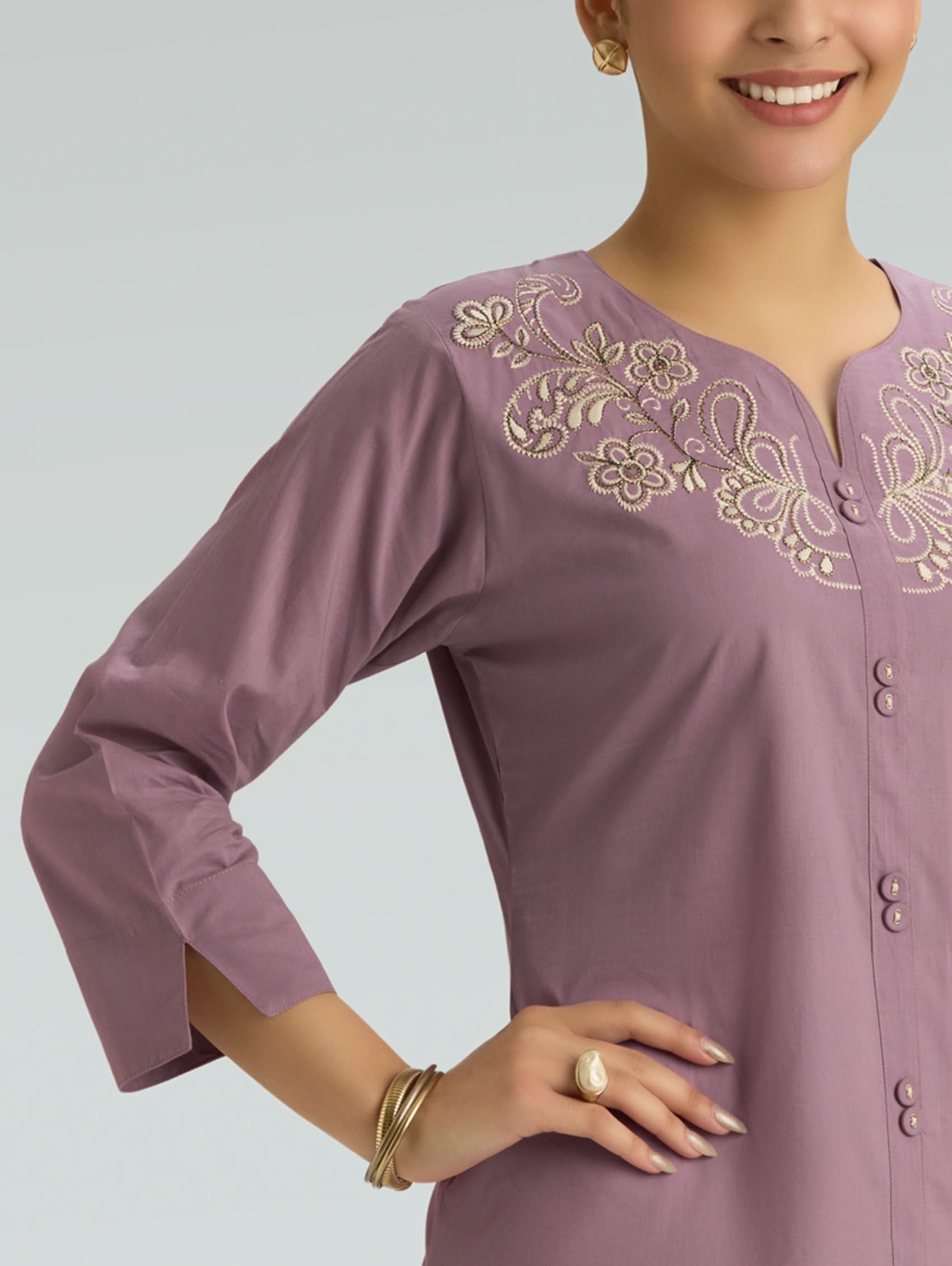 Purple embroidered top worn by a model on a gray background